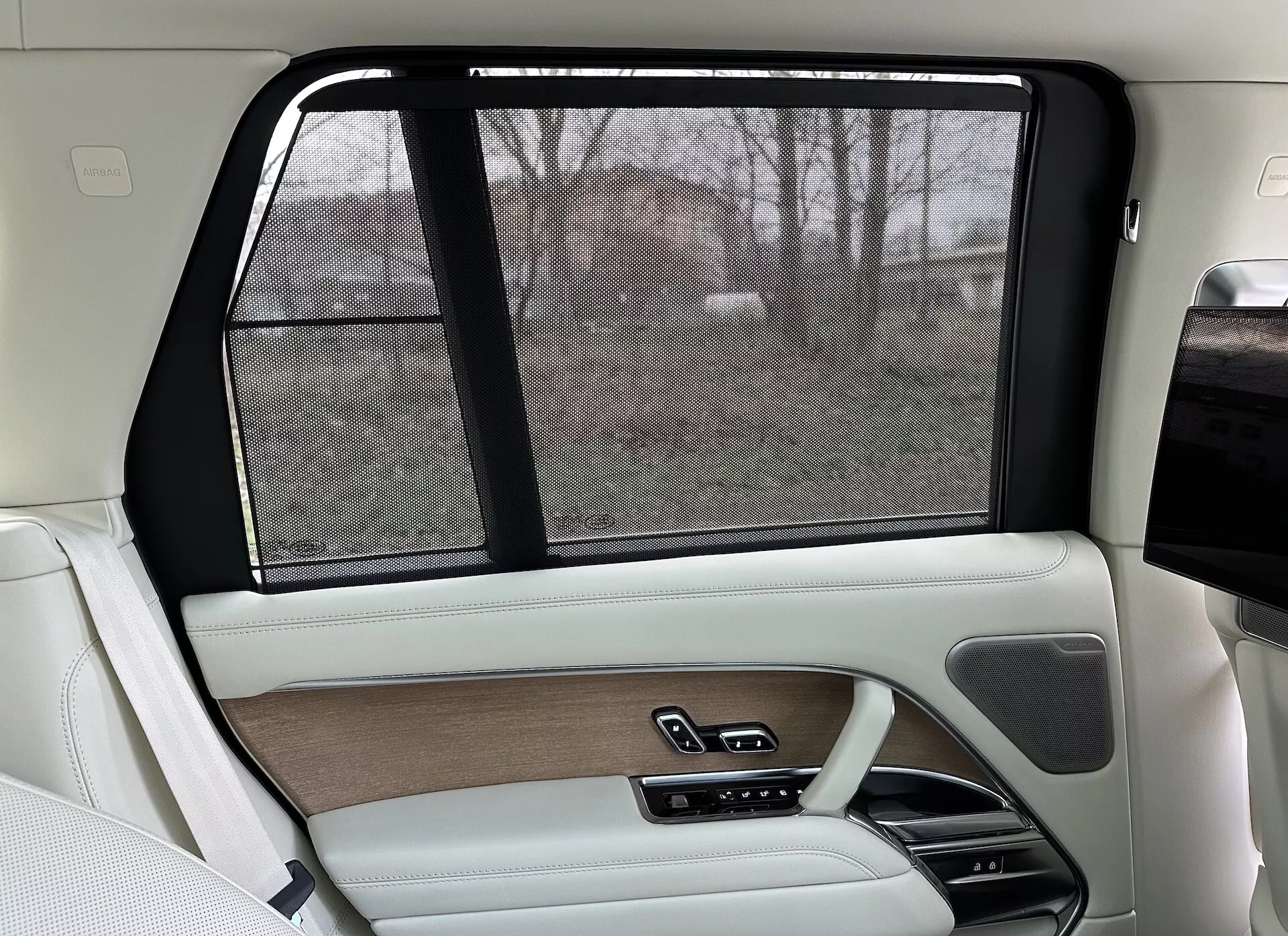 Interior del lado del pasajero trasero de un Land Rover Range Rover 2021, con diseño de lujo en beige y negro, adornos de madera, acabados en cuero, cortinilla solar electrónica y sistemas de control avanzados