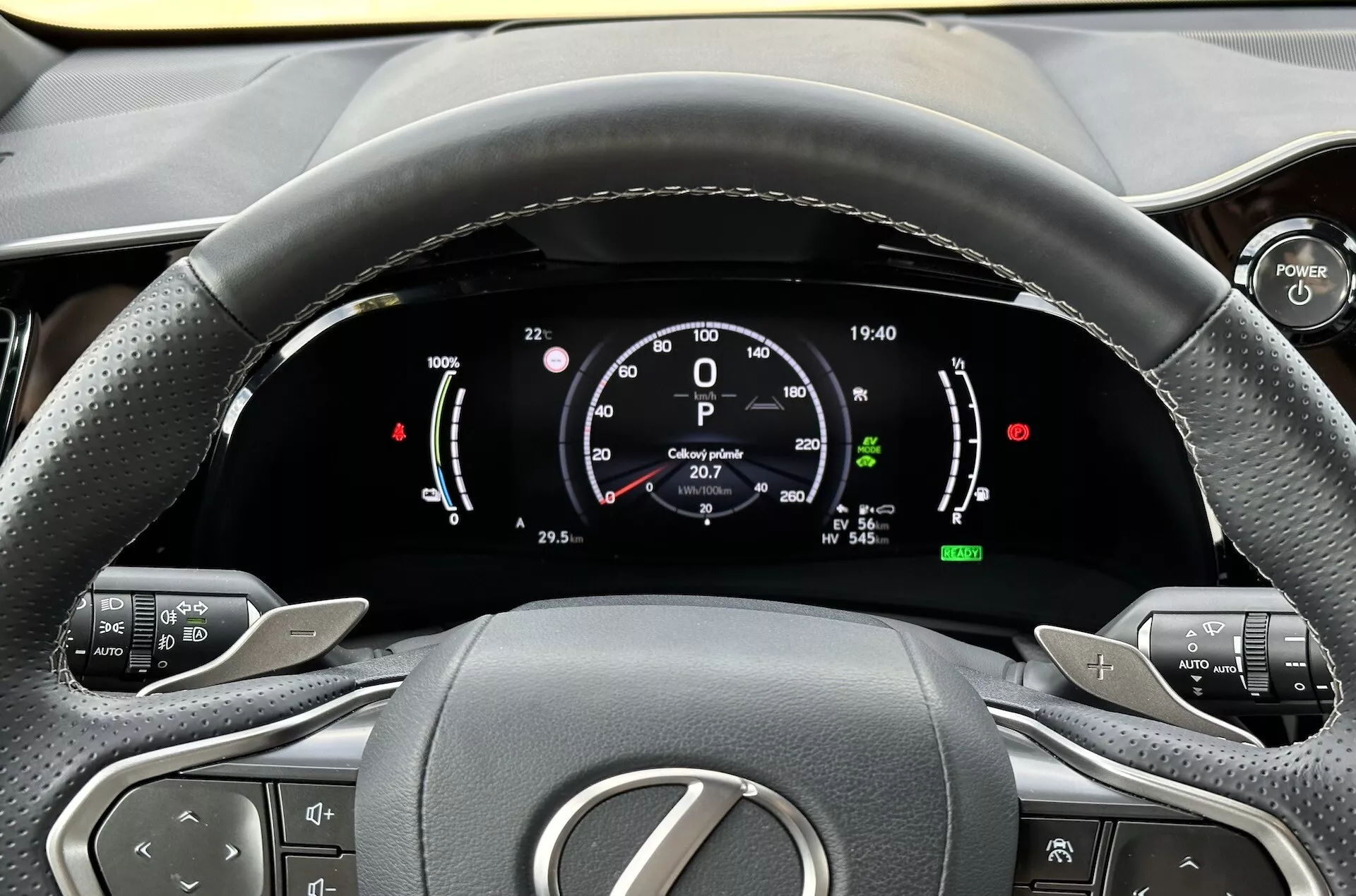 Vista desde el asiento del conductor del volante y el cuadro de instrumentos digital del Lexus NX 2021, destacando indicadores de tecnología híbrida, botones de control de confort y diseño interior ergonómico