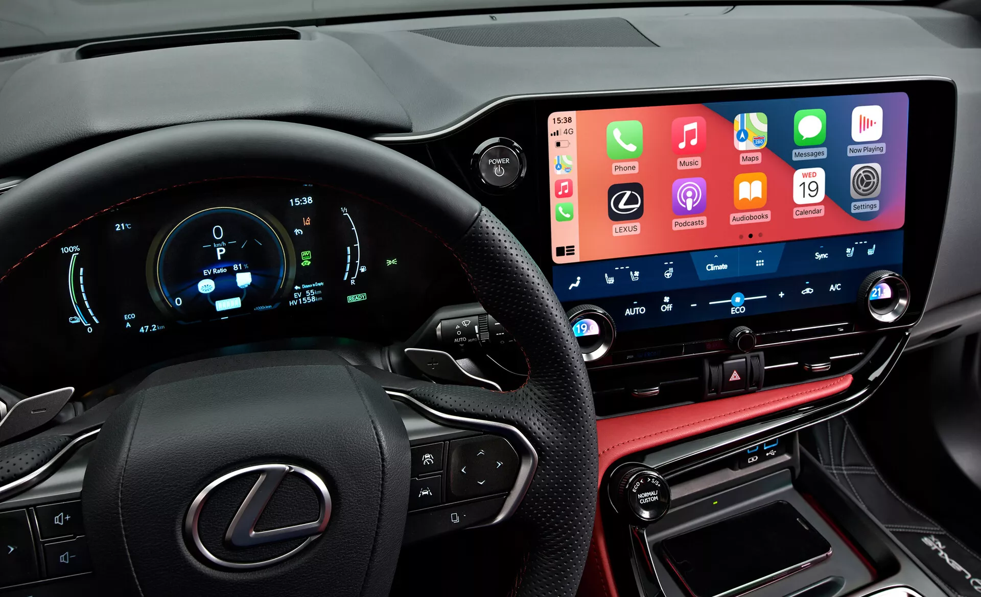Vista interior de un Lexus NX 2021 mostrando un tablero moderno y de alta tecnología desde la perspectiva del conductor. A la izquierda se ve parcialmente el volante con el logotipo de Lexus y botones multifunción. El panel de instrumentos digital muestra la velocidad, rpm y otras métricas en azul y blanco. En el centro, la pantalla táctil de infoentretenimiento amplia y prominente integra funcionalidades de smartphones. Debajo se encuentran los botones y diales de control de clima con pantallas de temperatura digitales. La sección inferior incluye una consola con costuras de cuero, la palanca de cambios y puertos de conectividad, reflejando los acabados lujosos del vehículo.