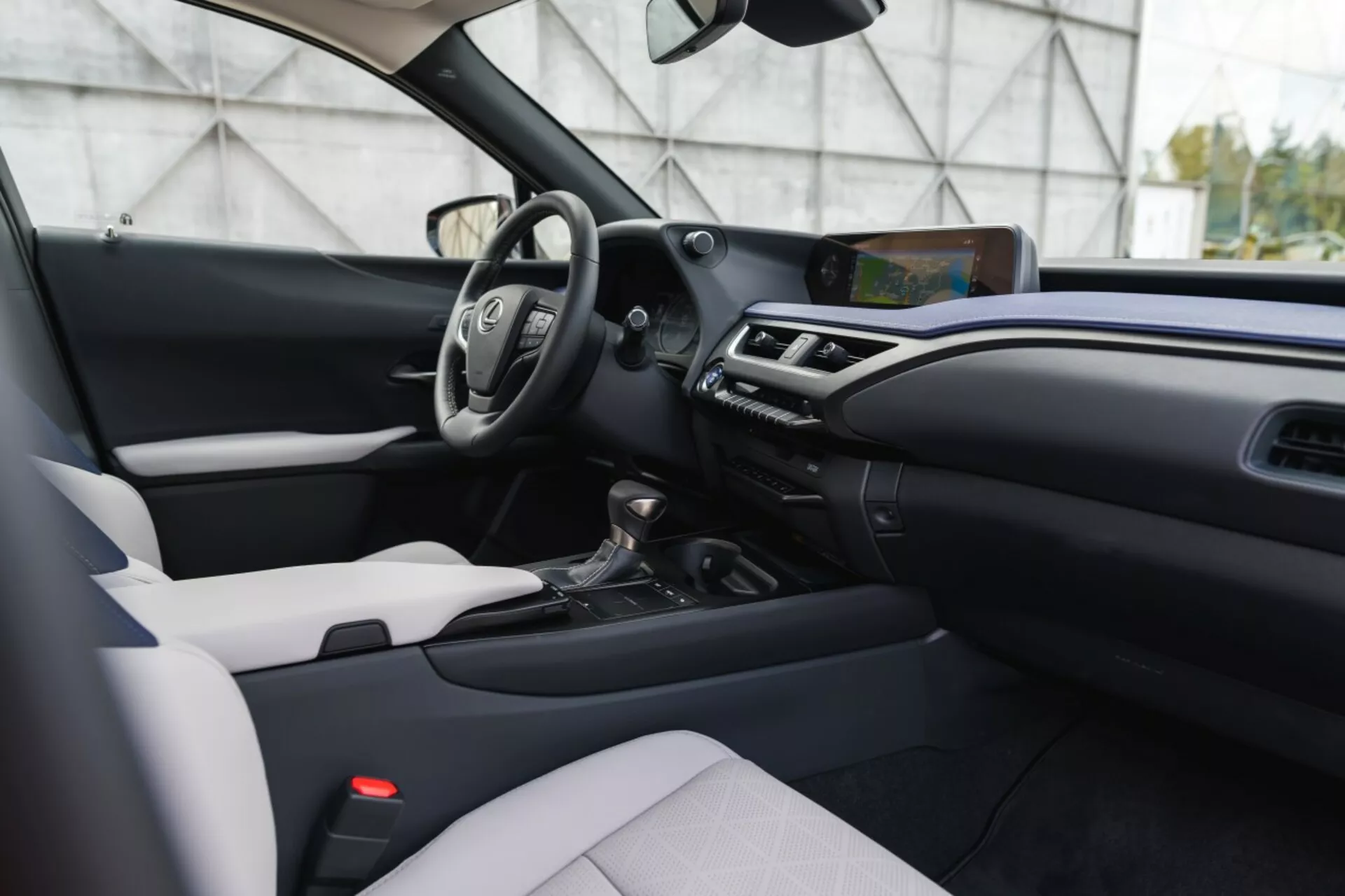 Interior moderno del Lexus UX 2019 mostrando un diseño en dos tonos, volante multifunción, pantalla de infoentretenimiento prominente y transmisión automática desde una perspectiva lateral y a nivel de los ojos
