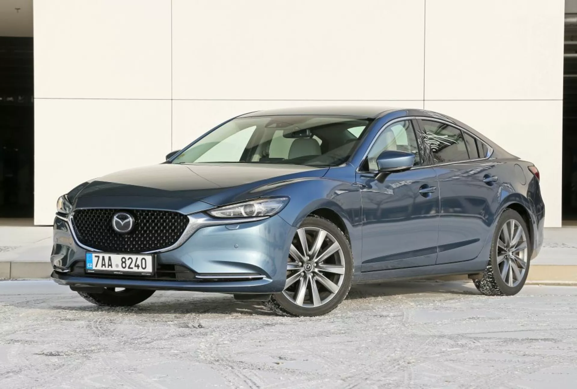 Sedán Mazda 6 de 2013 en azul, mostrando ángulo frontal de tres cuartos para una vista clara de la parrilla frontal, emblema, faros elegantes y ruedas de aleación en asfalto invernal