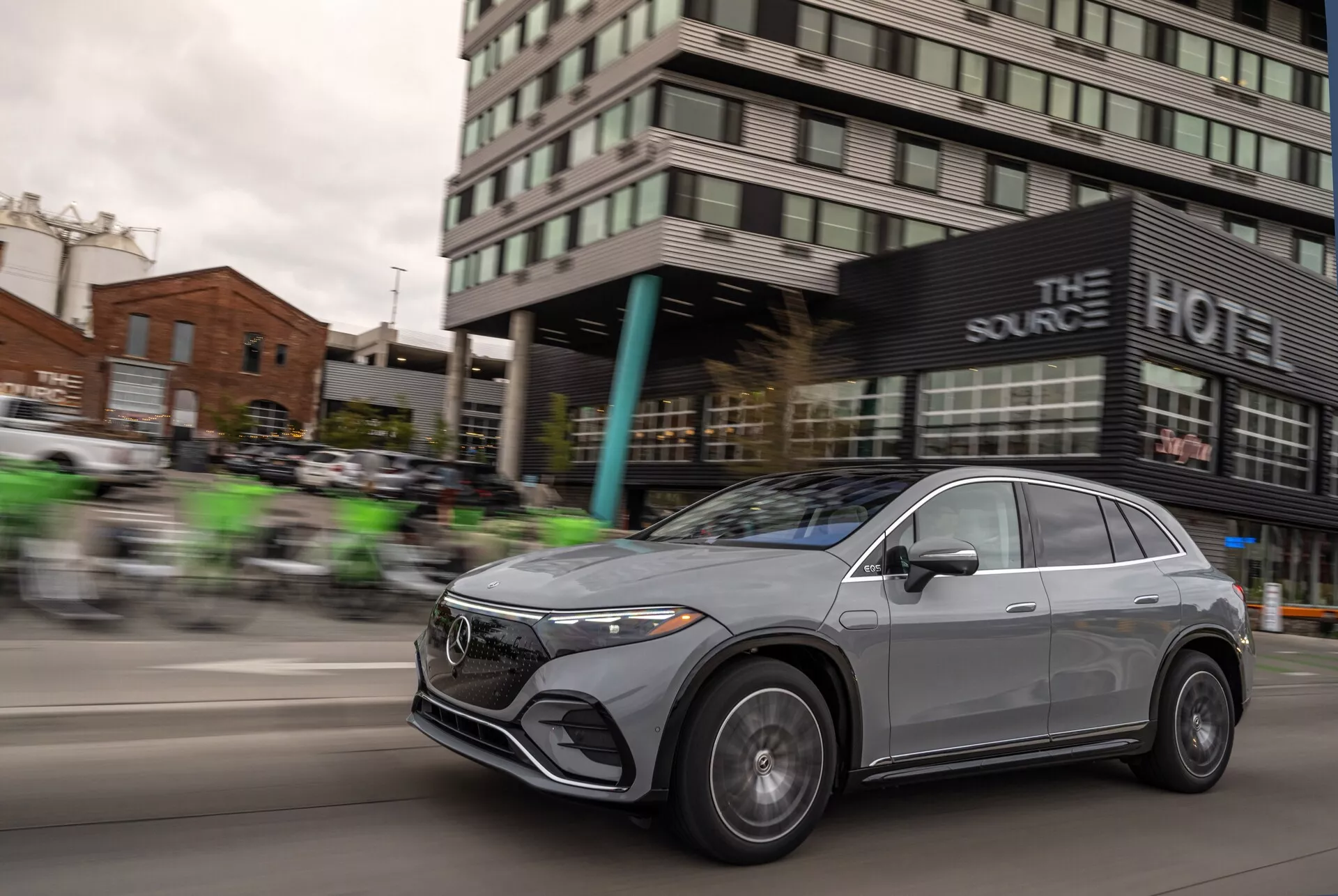 Una foto dinámica del Mercedes EQS-SUV 2022 en movimiento, con un efecto de desenfoque panorámico que resalta la velocidad del vehículo. La parrilla frontal, los faros LED, las llantas de aleación y el diseño aerodinámico del capó y la línea del techo son prominentes, destacando sus elementos sofisticados y lujosos. El acabado metálico del coche y su estilo crossover con ventanas elegantes sin marco y espejos aerodinámicos aumentan su atractivo moderno y exclusivo.