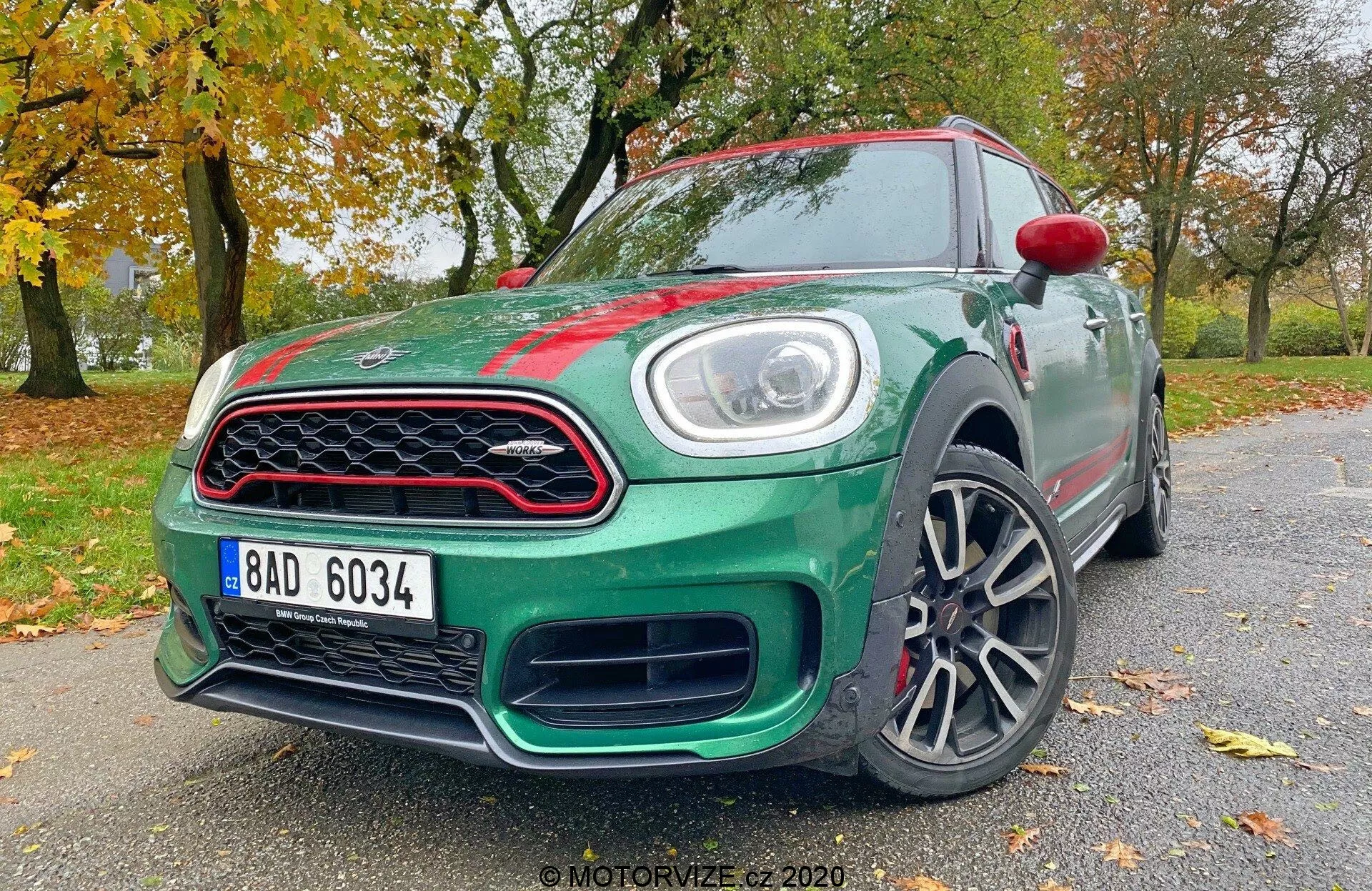La imagen muestra un hatchback 2020 Mini Countryman John Cooper Works, captado desde un ángulo bajo de tres cuartos delantero. Se pueden ver elementos clave de diseño y tecnología, incluyendo luces LED, una parrilla delantera distintiva, un parachoques estilizado, llantas de aleación, espejos laterales parcialmente visibles con señales de giro integradas, líneas aerodinámicas del cuerpo, insignias y el acabado de pintura brillante del coche. Esta perspectiva resalta la postura agresiva y el diseño dinámico del vehículo.