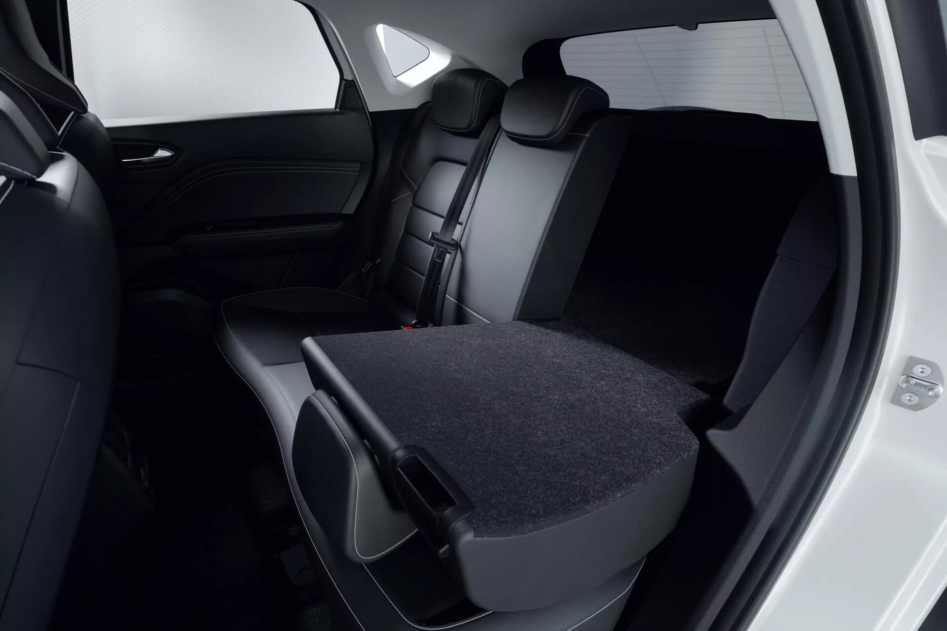 Vista de cerca del interior del pasajero trasero del Mitsubishi ASX 2023 (2ª generación). Enfocado en los asientos tapizados en cuero o cuero sintético oscuro, donde el asiento trasero derecho está abatido, mostrando la flexibilidad de carga. La puerta trasera está abierta revelando un interior a juego oscuro y ventanas tintadas. El diseño moderno y minimalista es evidente en la paleta de colores negro o gris oscuro. La imagen resalta la capacidad de almacenamiento del vehículo y el compromiso con la seguridad con reposacabezas y cinturones de seguridad visibles.