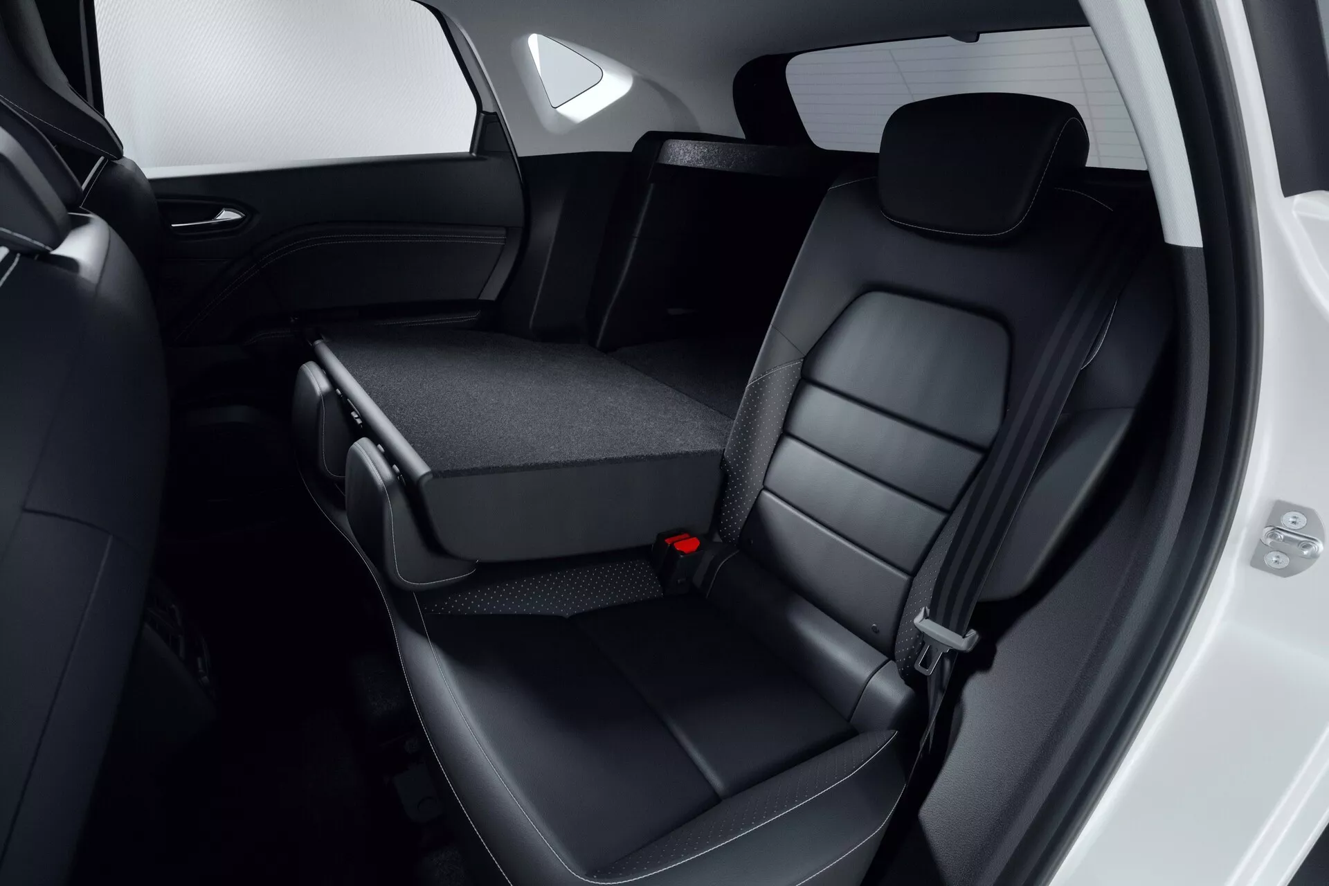 Vista interior de la zona de asientos traseros del Mitsubishi ASX 2023 (2ª generación), con asientos traseros tapizados en cuero negro con reposacabezas y costuras detalladas. El asiento central parcialmente abatido revela portavasos o área de almacenamiento, destacando el diseño abatible 60/40. El borde de la puerta del pasajero está abierto, mostrando elementos de diseño del panel de la puerta del automóvil. La imagen se centra en la comodidad, la calidad de los materiales y las características de conveniencia, cumpliendo con los estándares de seguridad moderna, incluidos los cinturones de seguridad de tres puntos.