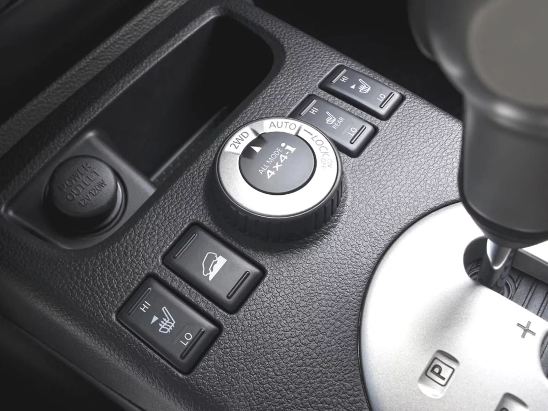 Vista detallada de la consola central del Nissan X-Trail 2010 con dial de control 4WD, botones de calefacción de asientos, botón de toma de corriente y palanca de cambios con modo de cambio manual