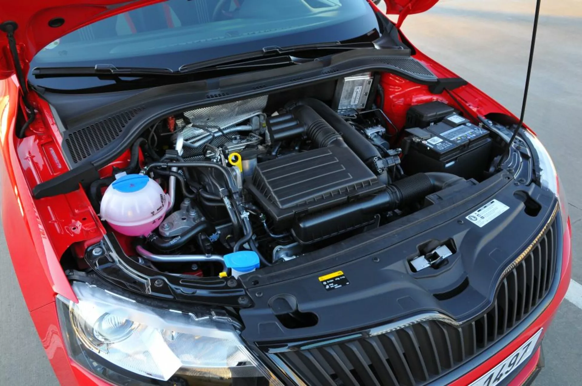 Vista detallada del compartimiento del motor abierto de un Opel Astra 2005 (Astra TwinTop), destacando componentes mecánicos como la caja de admisión de aire, cubierta del motor, depósitos de líquido refrigerante y de frenos, y batería desde una perspectiva frontal-elevada