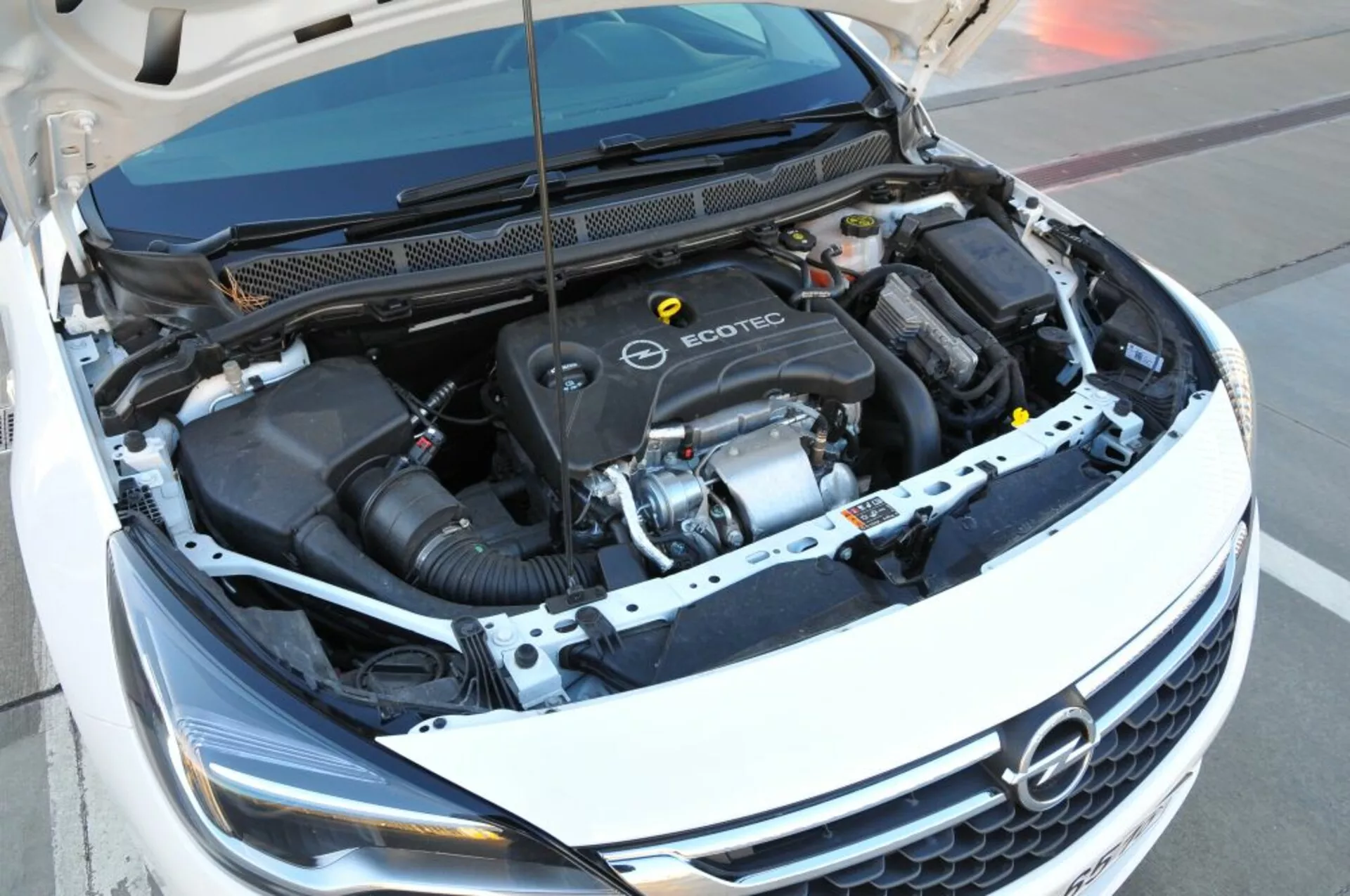 Vista en ángulo alto del compartimento del motor Ecotec del Opel Astra 2005, mostrando el bloque del motor, la manguera de admisión de aire y varios componentes