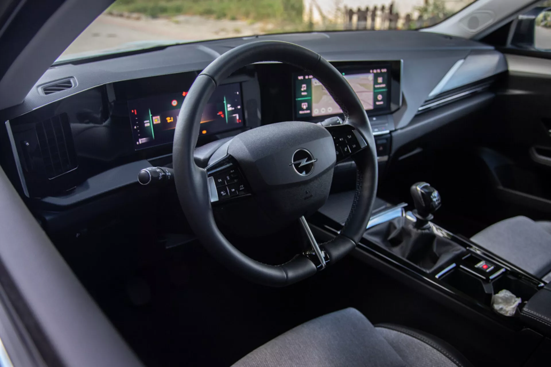 Interior del Opel Astra 2022 mostrando el asiento del conductor, un tablero tecnológicamente avanzado con el logotipo de Opel en el volante, indicadores digitales y paneles táctiles verticales dobles