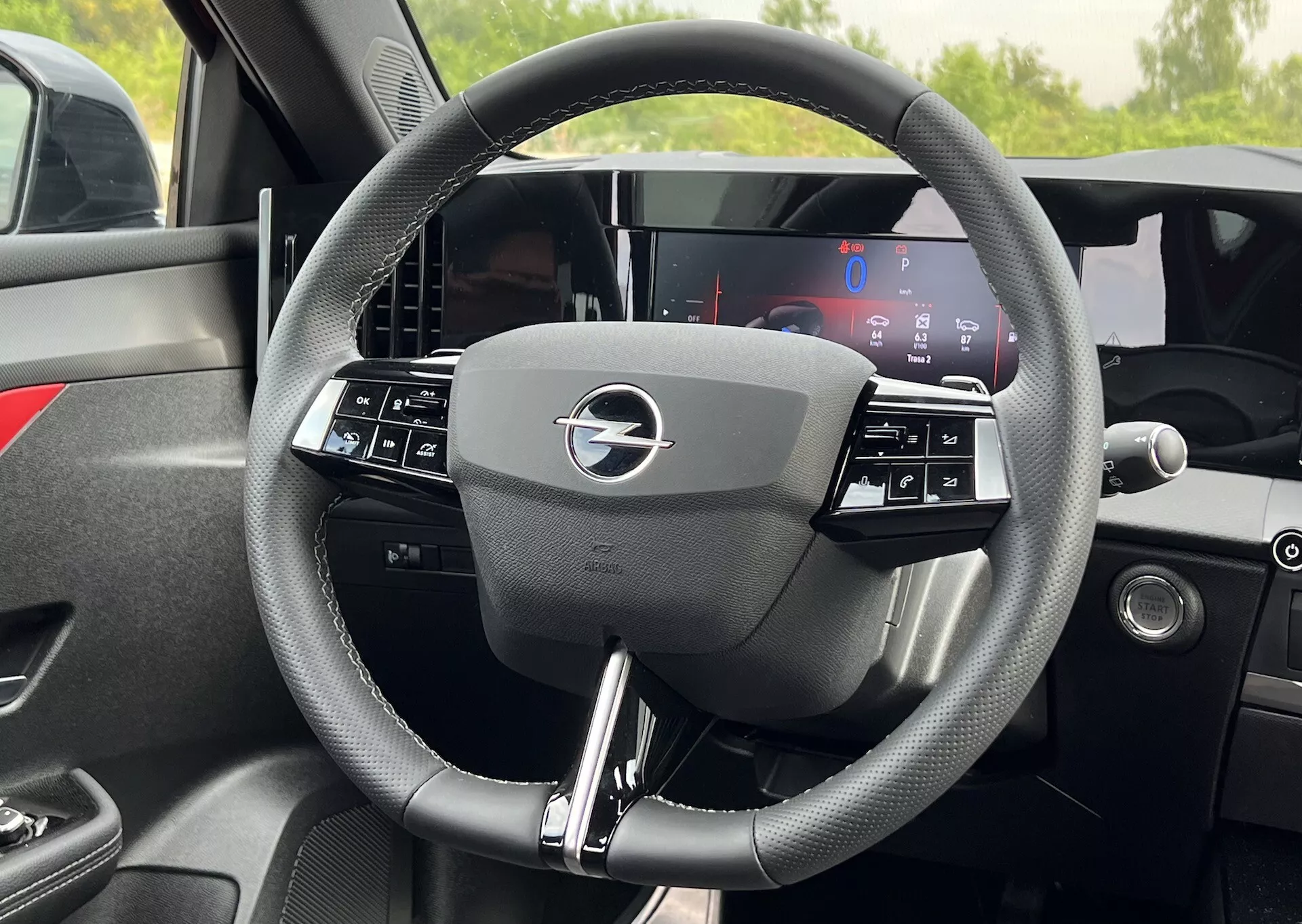 Vista interior detallada del volante del Opel Astra 2022 con diseño de tres radios con controles integrados y un tablero de instrumentos completamente digital detrás, destacando la tecnología moderna del vehículo y la ergonomía