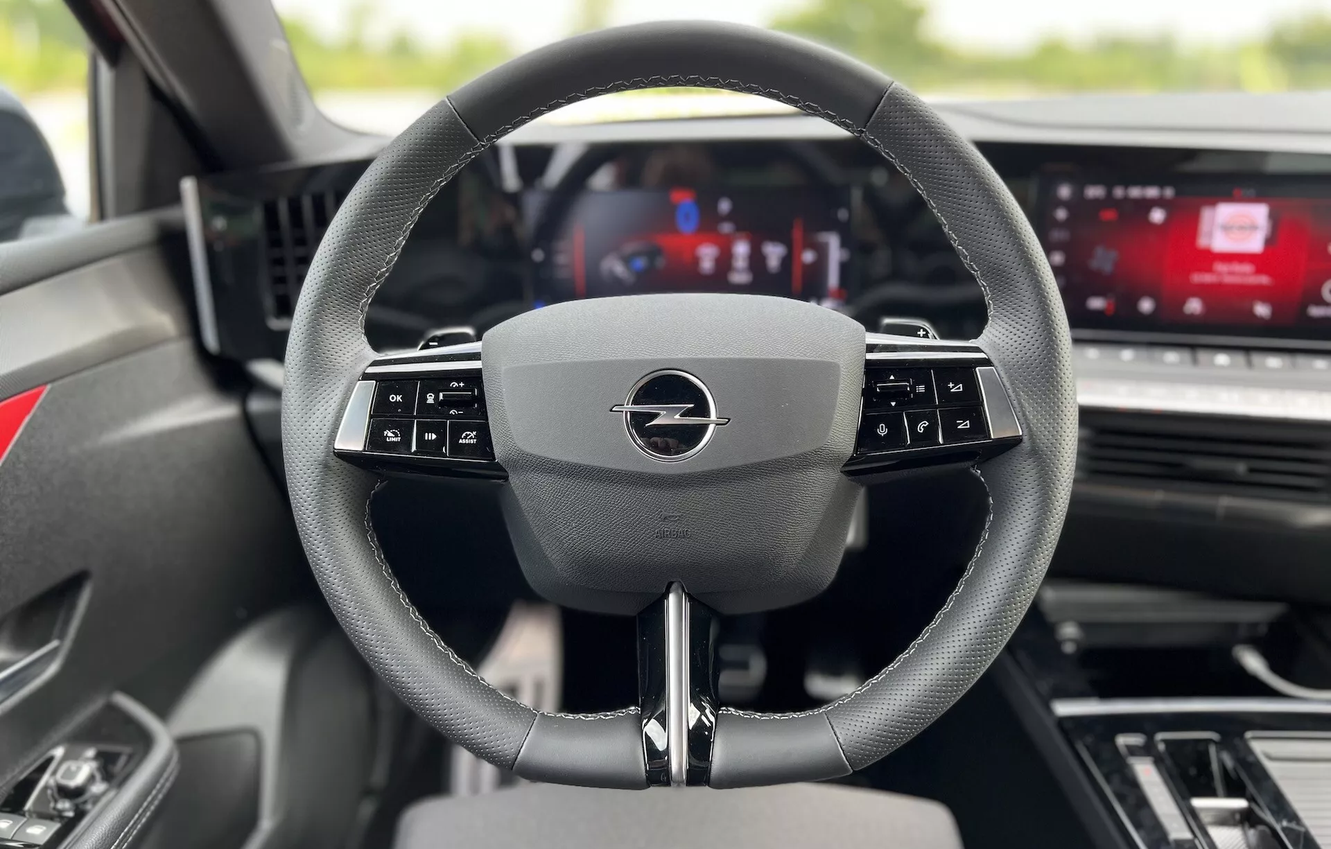 Vista interior de Opel Astra 2022 desde el asiento del conductor centrada en el volante multifuncional moderno y el panel de instrumentos digital