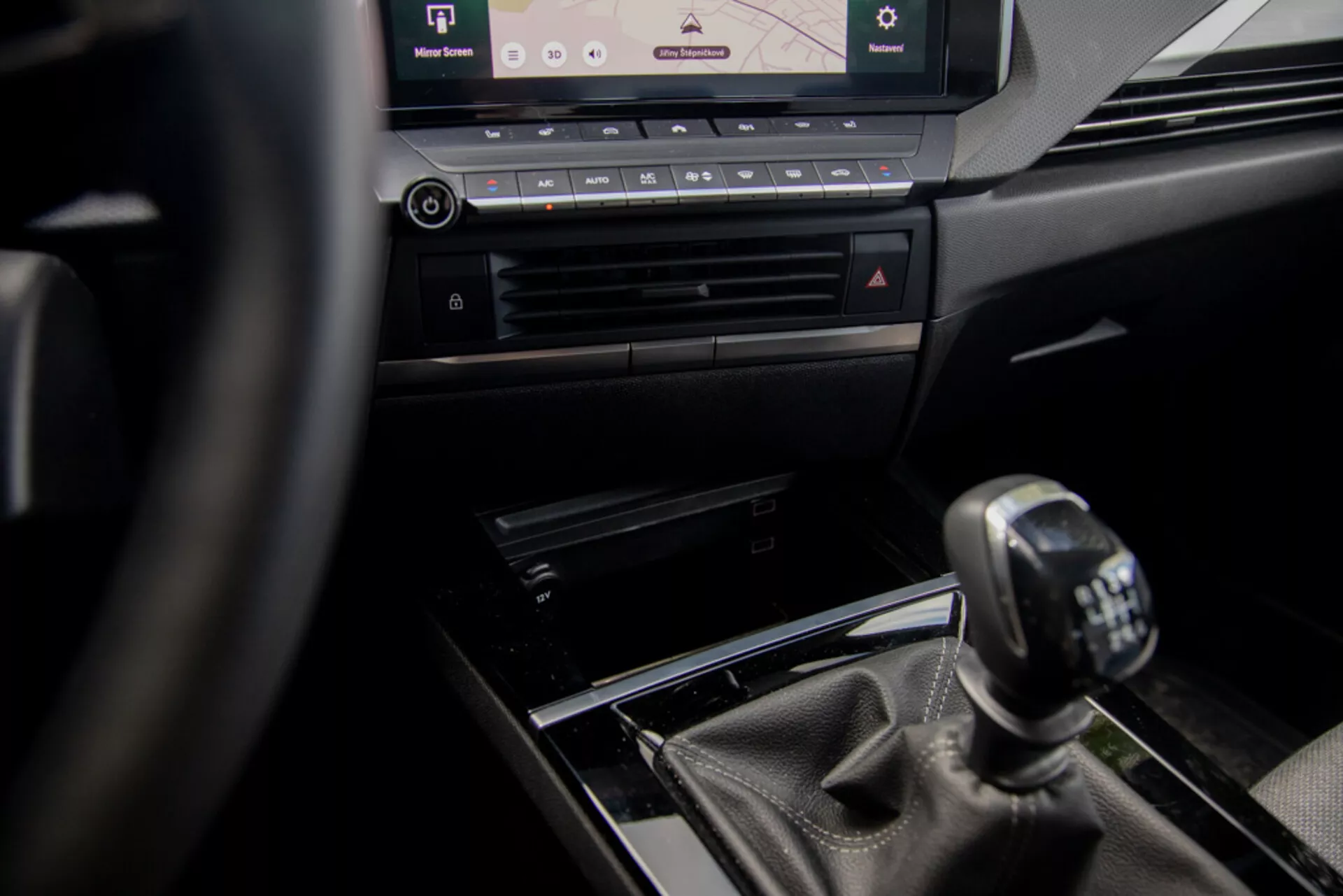 Vista interior del Opel Astra 2022 centrada en la consola central y el cambio de marchas manual desde la perspectiva del conductor, con volante, elementos de diseño de lujo y sistema de infoentretenimiento moderno.