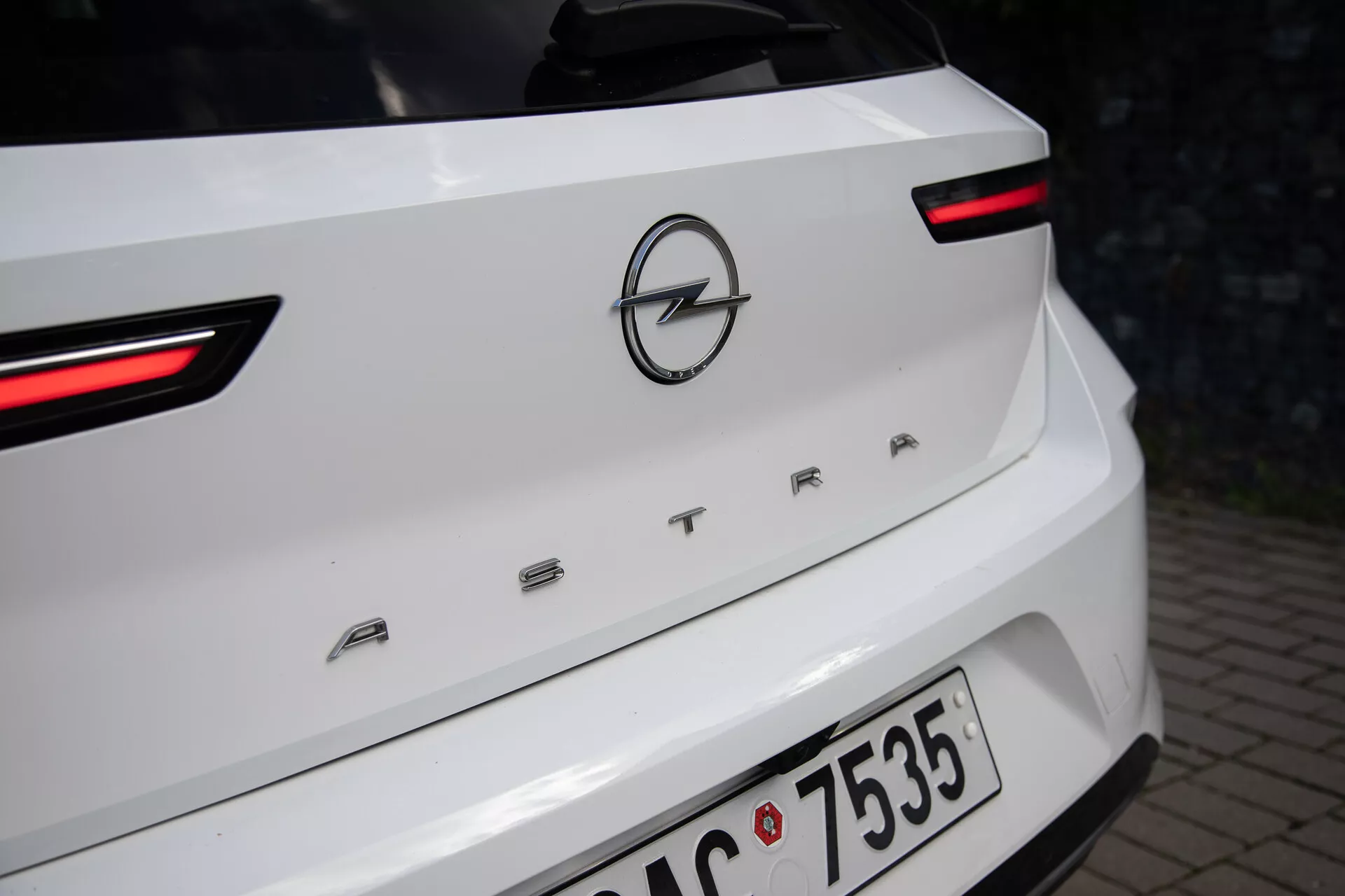 Vista detallada de la parte trasera de un Opel Astra blanco de 2022, destacando las luces traseras LED, el logo de Opel y el nombre del modelo 'ASTRA' en la tapa del maletero