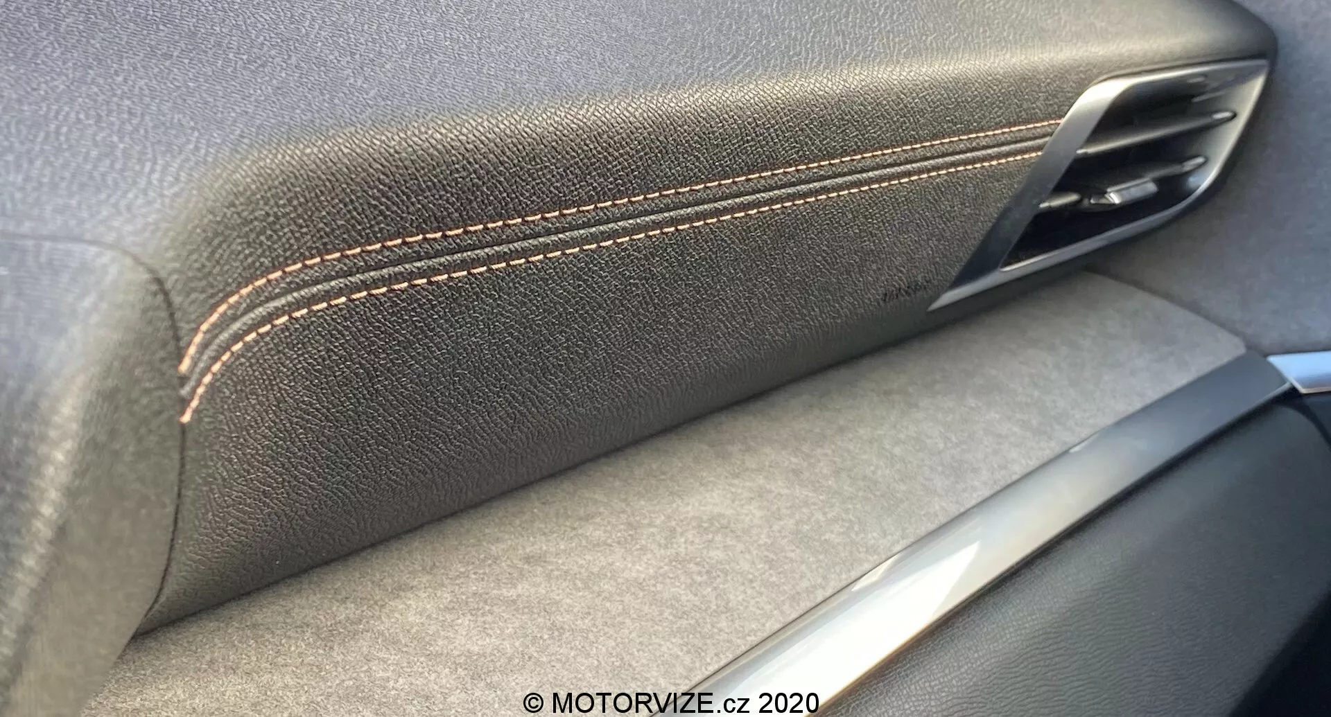 Toma interior en primer plano del panel de puerta del Peugeot 3008 2021, destacando la convergencia del reposabrazos con textura de cuero y costuras contrastantes y la manija de la puerta metálica. Los acentos plateados sugieren un enfoque en la artesanía y calidad de los materiales, con sombras que indican una fuente de luz interior.