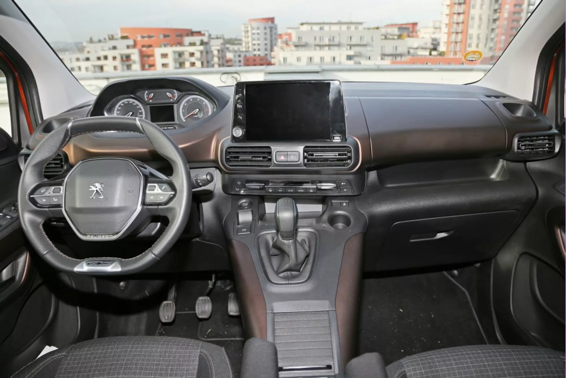 Vista interior de un Peugeot 3008 de 2016 mostrando el tablero de instrumentos, el volante con controles montados y la pantalla táctil central del sistema de infoentretenimiento desde la perspectiva del asiento trasero
