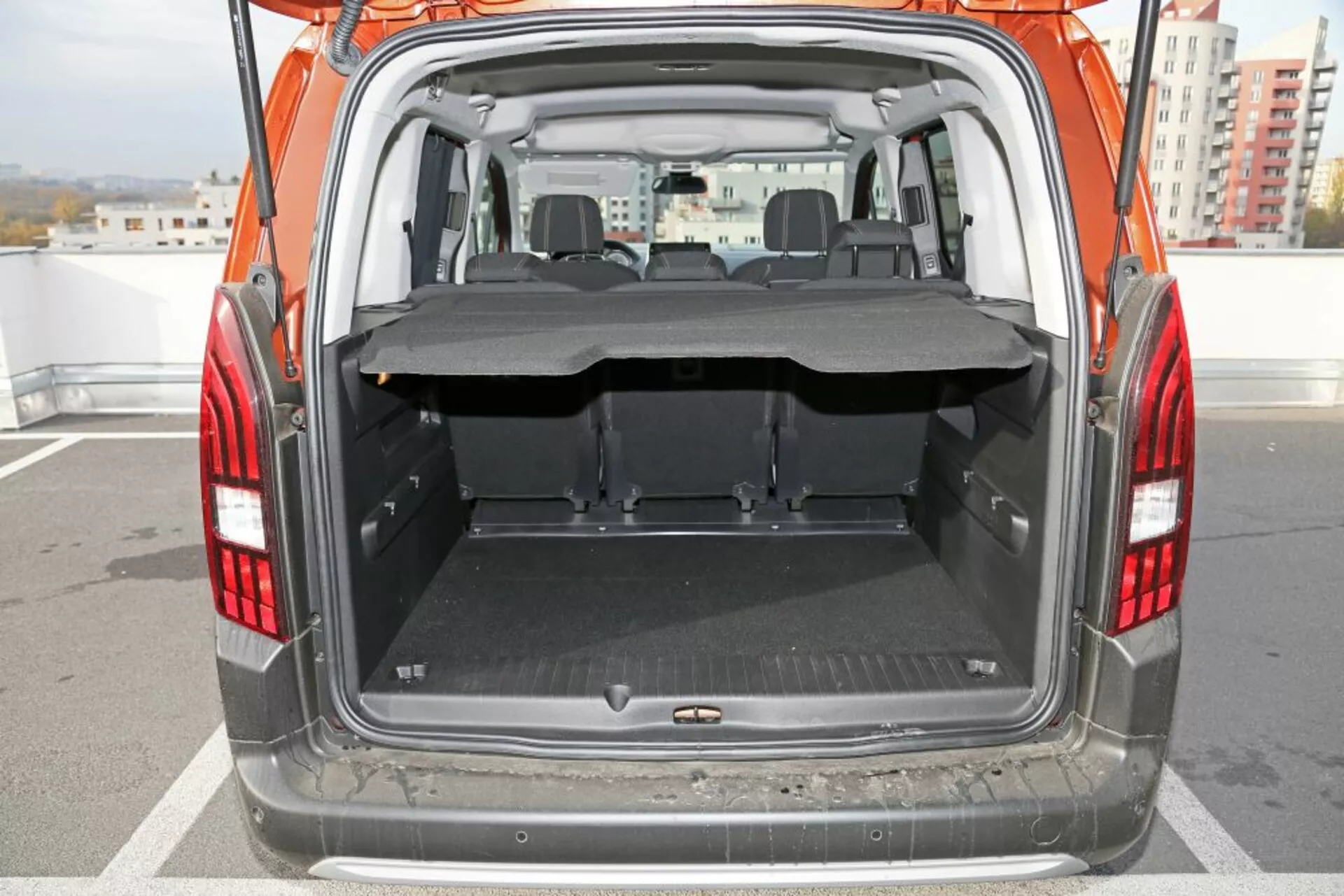 Vista trasera de un SUV Peugeot 3008 de 2016 centrada en el maletero abierto y el área de carga, con un suelo plano y limpio con una alfombra protectora, una cubierta de carga parcialmente extendida, asientos traseros plegables y clara visibilidad hacia el área de asientos delanteros a través de la parte trasera.