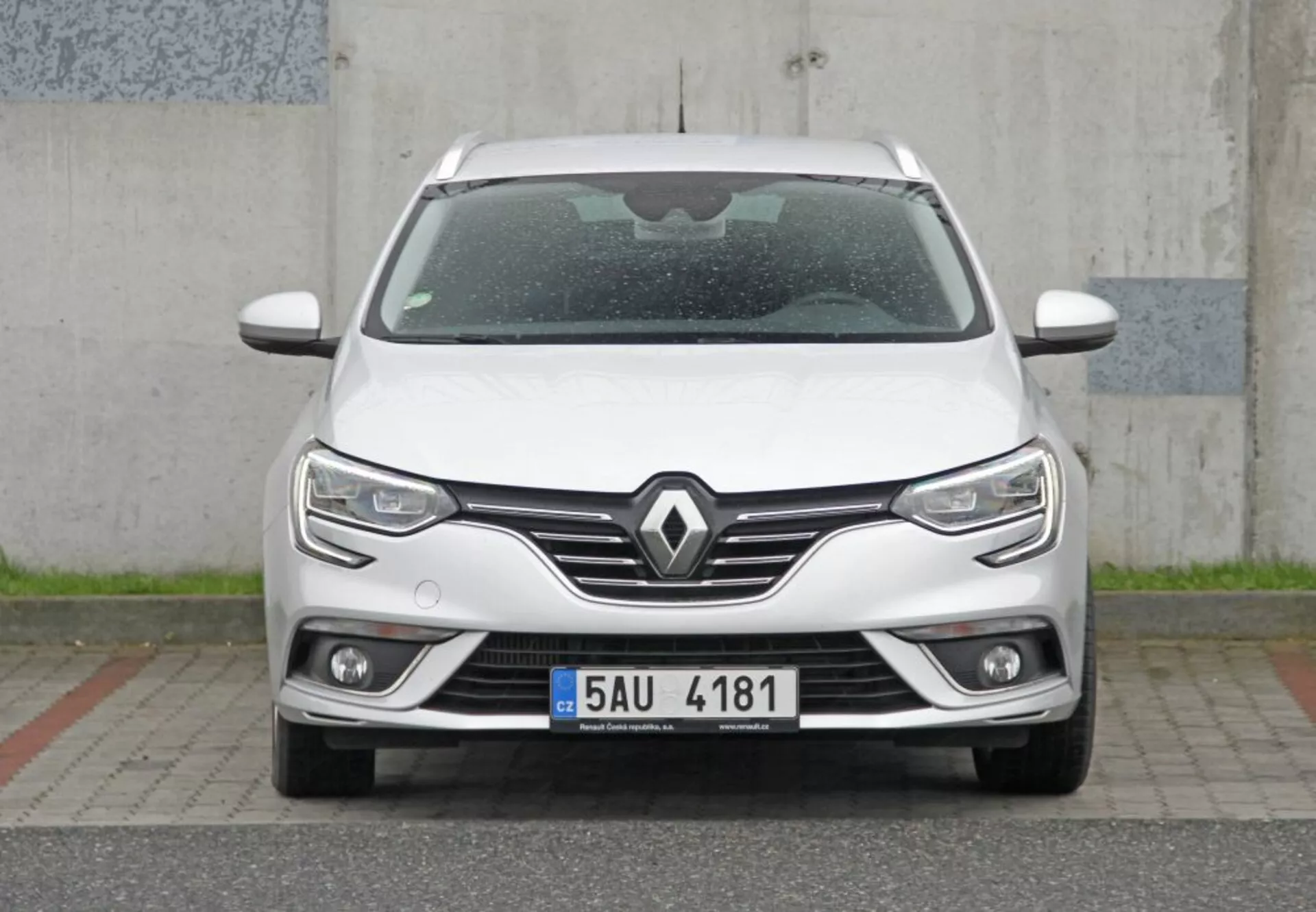 Vista frontal directa de un elegante Peugeot 308 SW 2013 blanco con parrilla prominente con emblema de Renault, faros LED modernos con luces diurnas, luces antiniebla integradas y tecnología de sensor de aparcamiento, enfatizando un diseño moderno y aerodinámico.