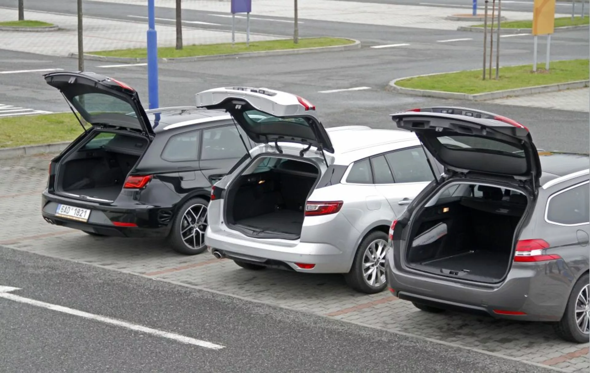 Tres vehículos familiares Peugeot 308 SW 2013 estacionados uno al lado del otro con las puertas traseras abiertas destacando el espacio de carga y el diseño del portón desde un ángulo elevado