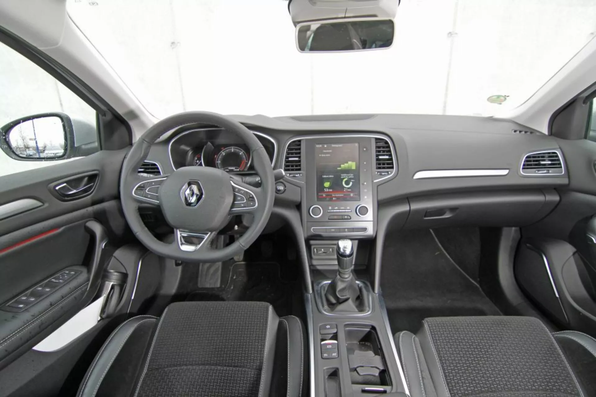 Vista interior del Peugeot 308 SW 2013 desde el asiento central trasero mostrando el tablero de mandos, volante con botones multifunción, cuadro de instrumentos, consola central con pantalla de infotenimiento, palanca de cambios automática, controles de clima, asientos delanteros de tela con cubo, paneles de puerta con controles, espejos laterales, techo del coche, espejo retrovisor, y esquema de colores oscuros moderno con acentos plateados