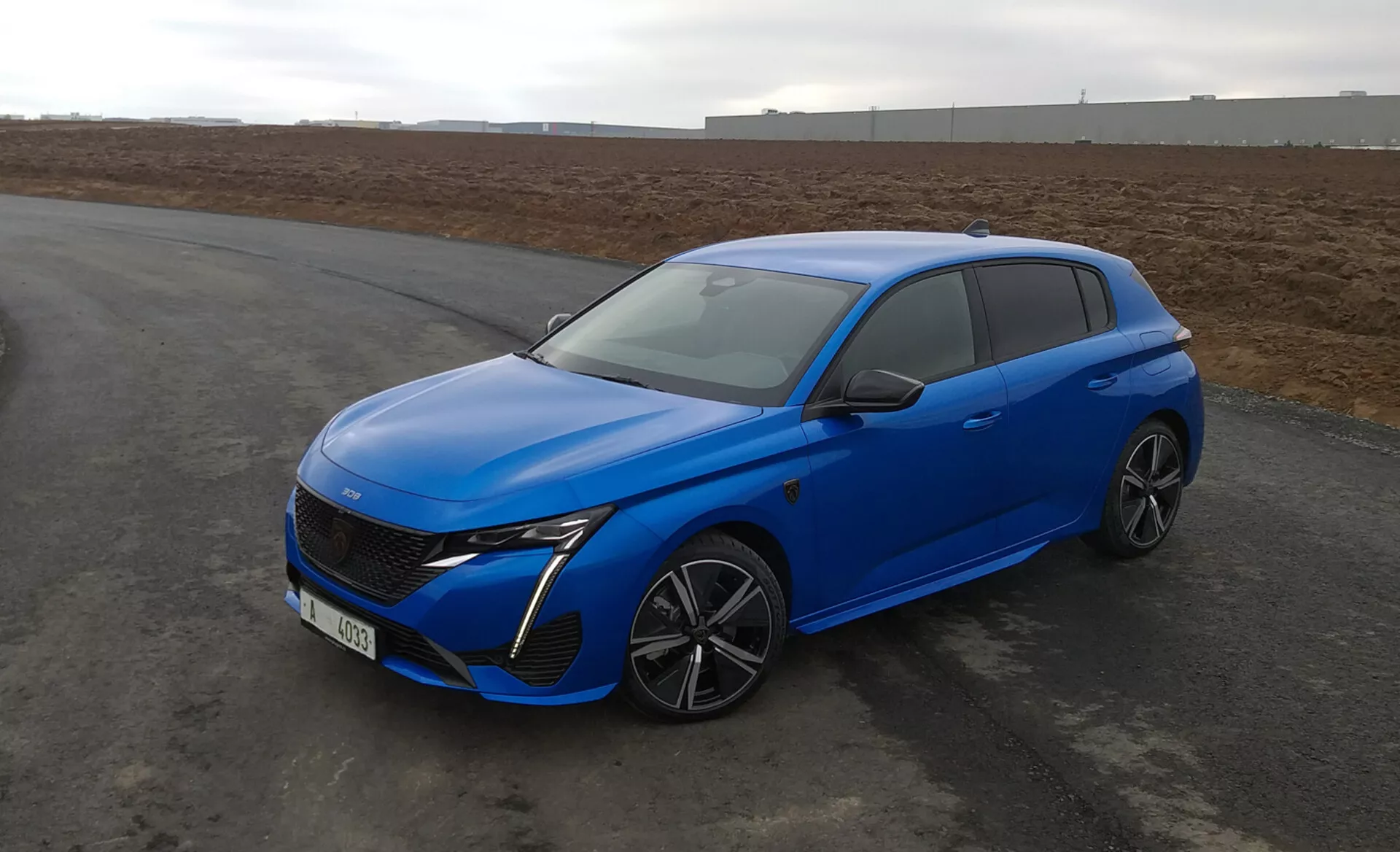 Peugeot 308 hatchback 2022 en azul brillante, con diseño aerodinámico, faros LED, parrilla delantera avanzada, llantas de aleación de múltiples radios y características de seguridad modernas, estacionado en el asfalto