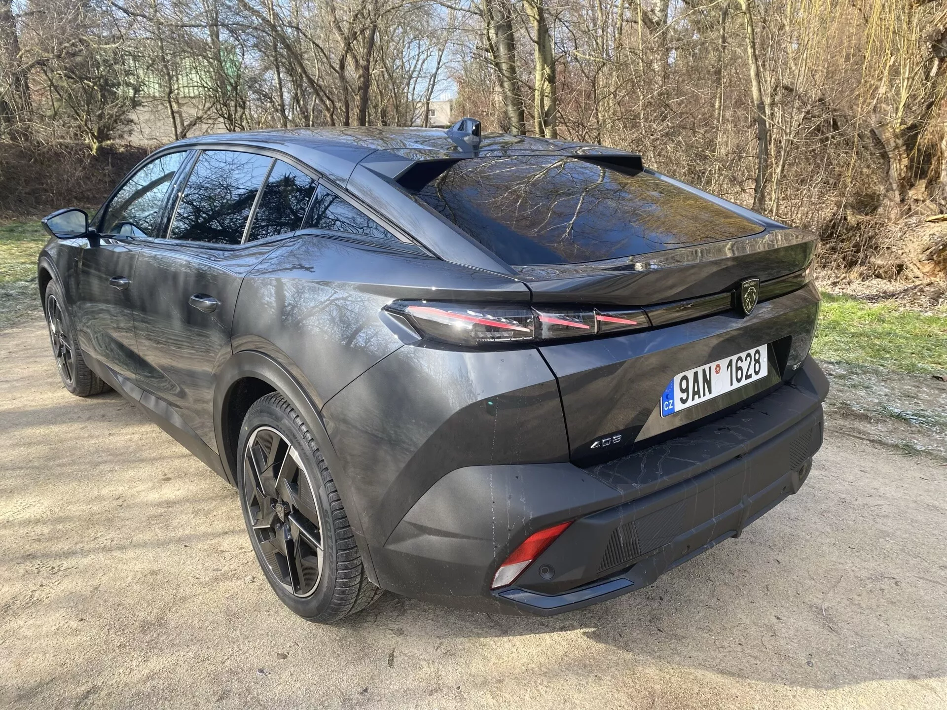 Peugeot 408 2023 con un diseño hatchback deportivo y aerodinámico, luces traseras LED con barra de luz trasera, ruedas de aleación negras y sistema de escape doble capturado desde un ángulo trasero de tres cuartos destacando su perfil lateral y parte trasera.