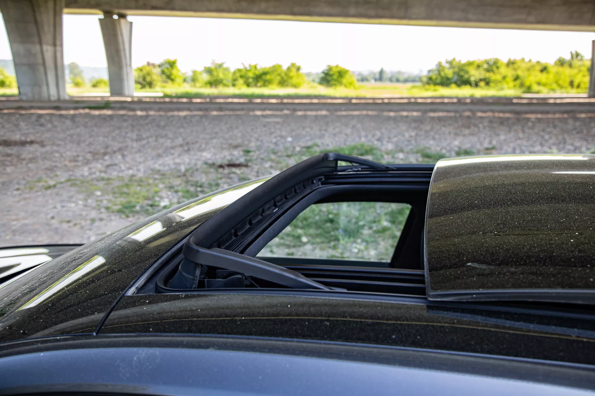 Vista detallada del mecanismo del techo convertible del Peugeot 408 2023, enfocándose en los puntos de conexión con la carrocería, capturada desde el lado del pasajero destacando el forro interior del techo blando, sellado contra el clima y la pintura exterior.