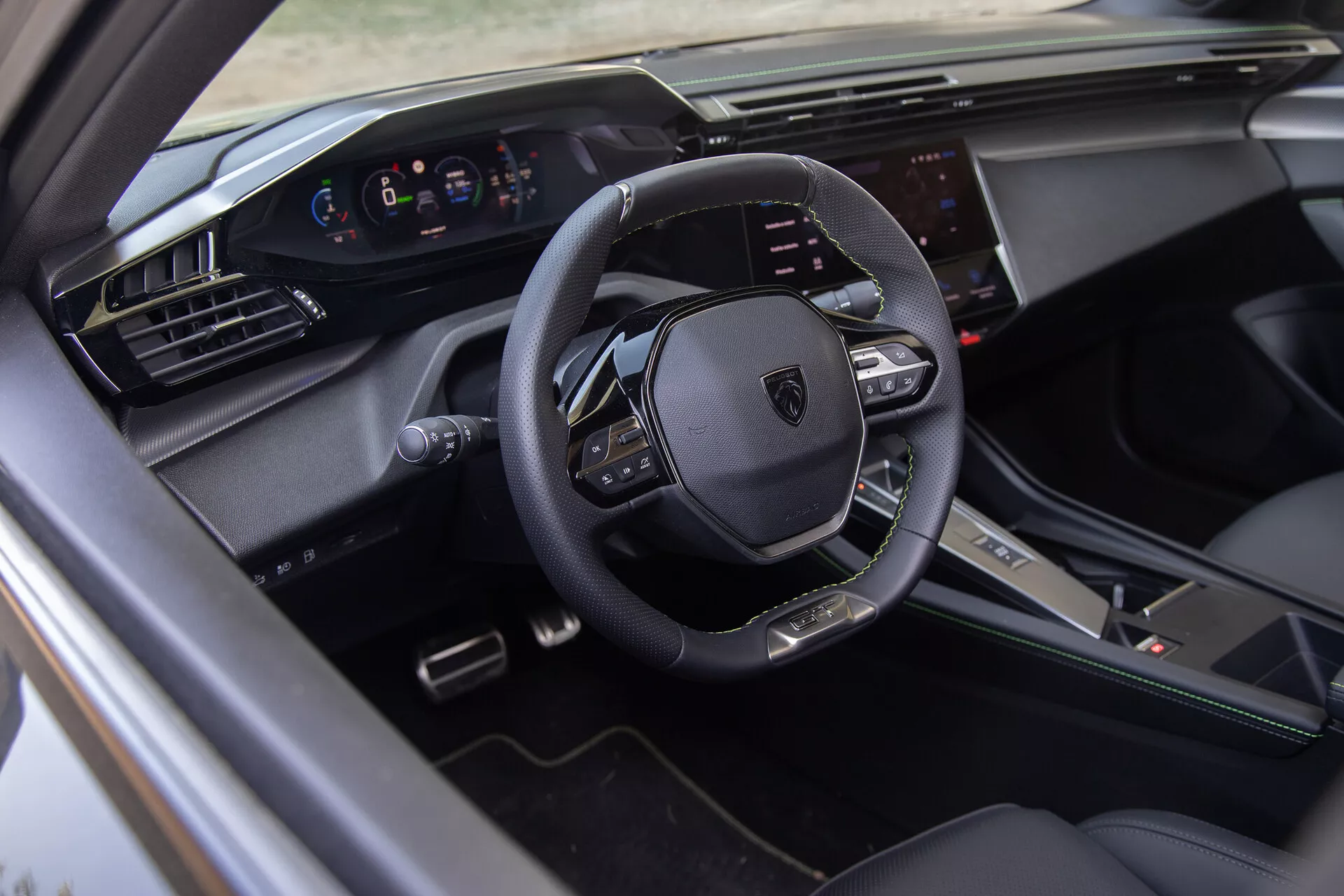 Interior del Peugeot 408 2023 mostrando un volante multifunción forrado en cuero, cuadro de instrumentos digital y sistema de infoentretenimiento táctil desde la vista del lado del conductor