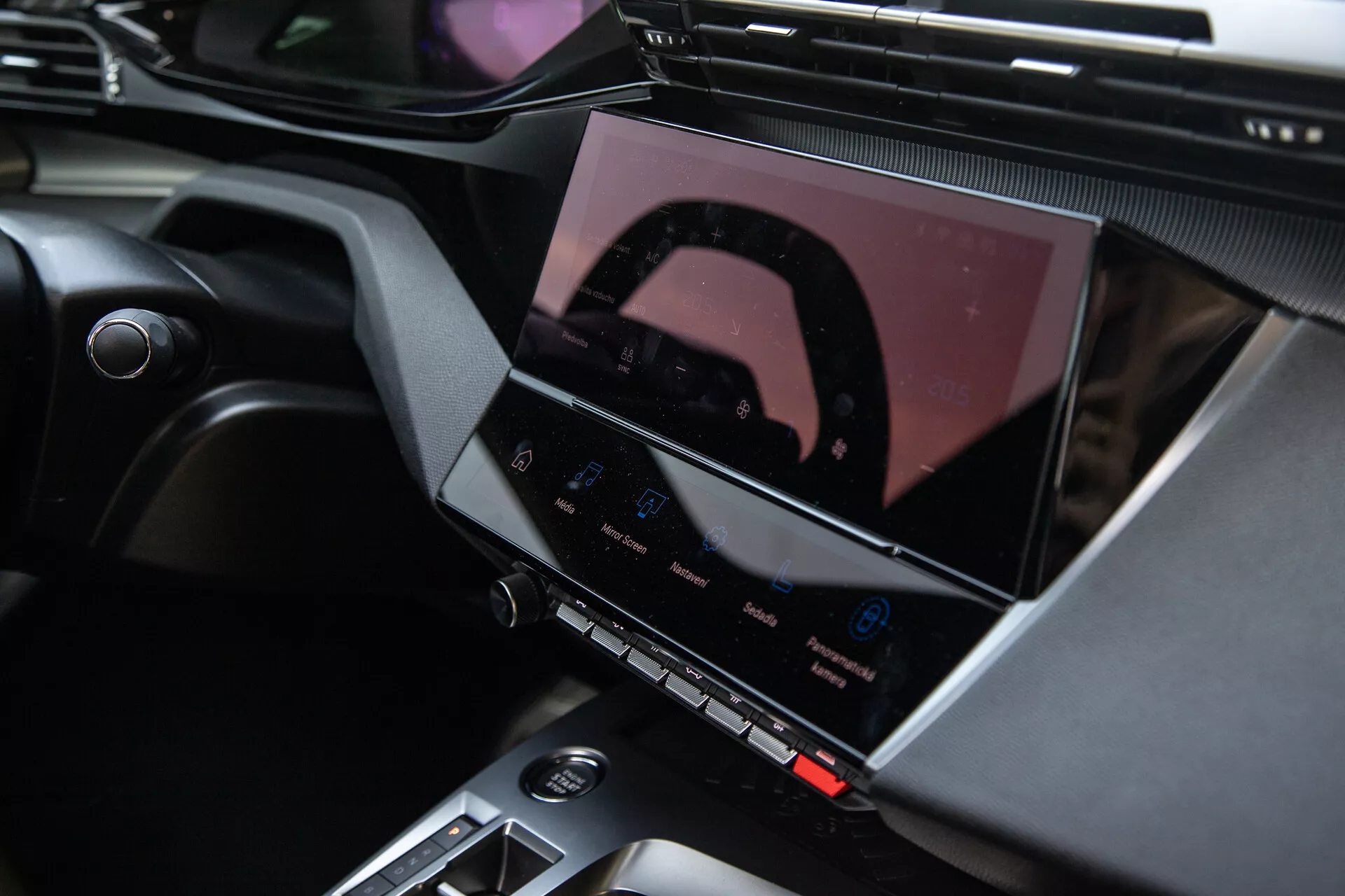 Interior del Peugeot 408 2023 mostrando la consola central y el avanzado sistema de infoentretenimiento con pantalla táctil, botones de control del clima y elegantes acentos de diseño