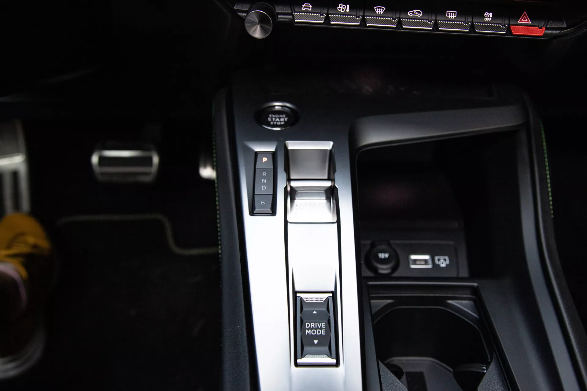 Vista cercana de la consola central del Peugeot 408 2023 con la palanca de cambios en posición de Parqueo, botón de MODO DE CONDUCCIÓN, freno de estacionamiento electrónico y puertos USB, mostrando diseño interior moderno.