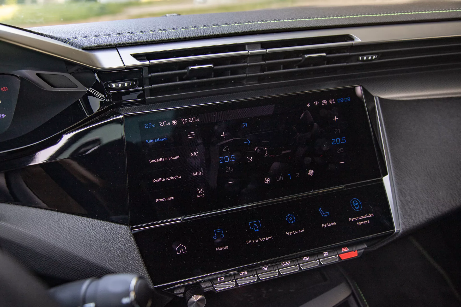 Primer plano del sistema de entretenimiento Peugeot 408 2023 con pantalla táctil de 8-10 pulgadas mostrando navegación, control climático, íconos de reproducción de medios y visión parcial del tablero, tomado desde el lado del pasajero