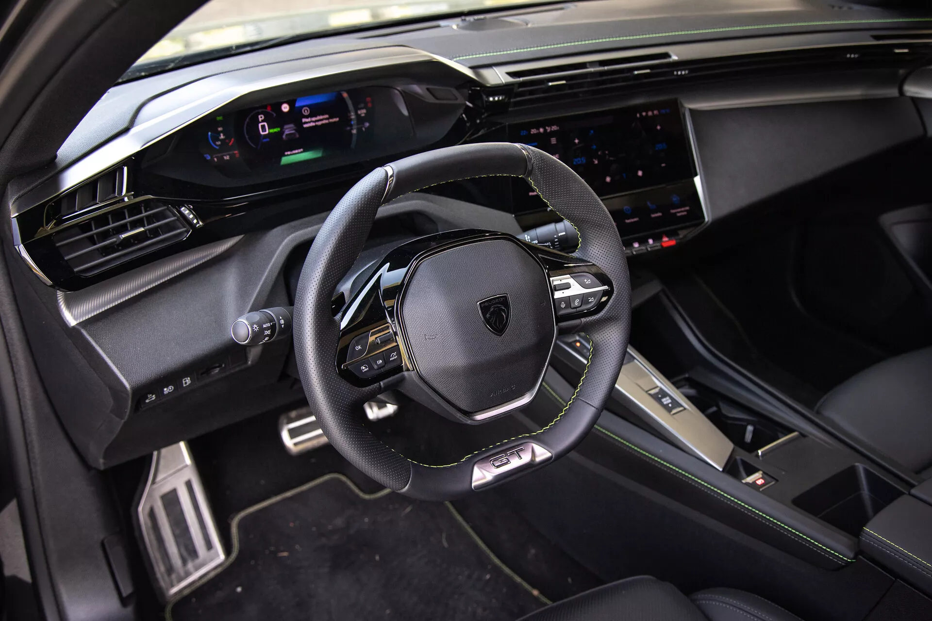 Interior del Peugeot 408 2023 con volante multifunción forrado en cuero, tablero de instrumentos digital, sistema de infoentretenimiento táctil amplio y elementos de diseño premium deportivos bajo luz natural desde la perspectiva del pasajero delantero.