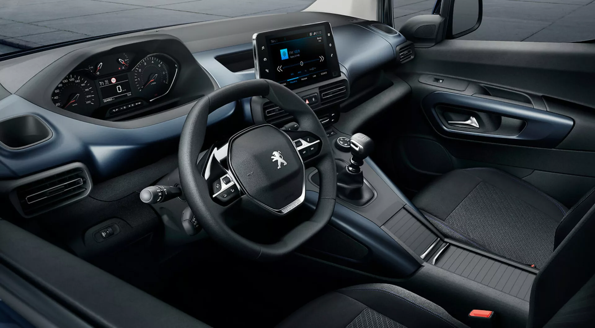 Vista elevada del interior del Peugeot Rifter 2018 con sistema de infotenimiento táctil, panel de instrumentos digital y volante de tres radios con controles integrados, destacando la excelencia tecnológica y de diseño
