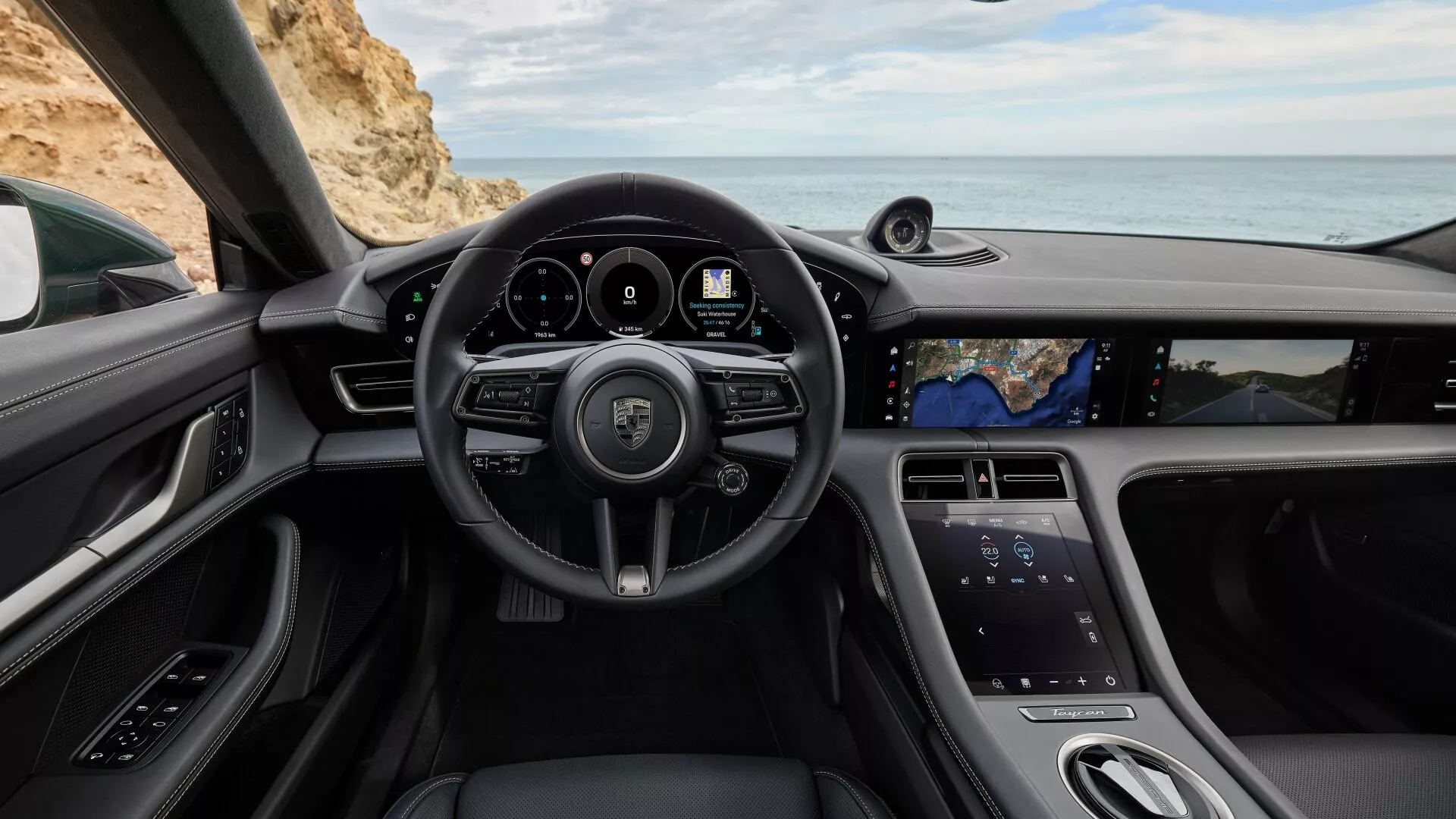 Vista interior del Porsche Taycan 2024 Y1A facelift desde el asiento del conductor con volante con logo, botones multifunción, levas traseras, cuadro de instrumentos digital, altavoz de sistema de sonido premium, asiento de pasajero en toma panorámica, pantalla táctil vertical grande para entretenimiento, y diseño elegante con detalles en cuero y cromo