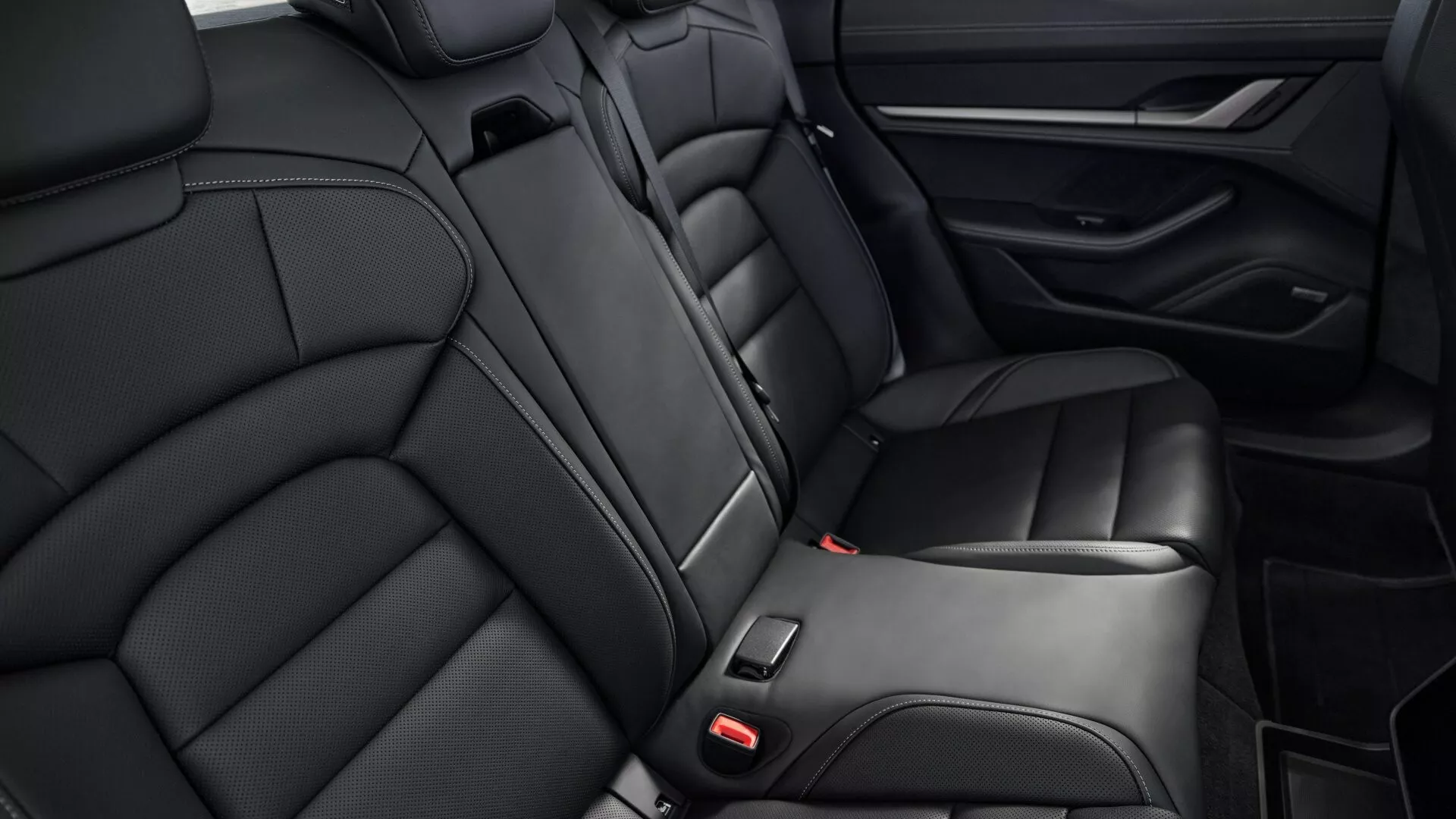 Vista cercana de los asientos traseros de cuero negro lujosos, reposabrazos integrado y diseño del panel de la puerta del Porsche Taycan Y1A facelift 2024, centrados en la comodidad y las características interiores de alta gama
