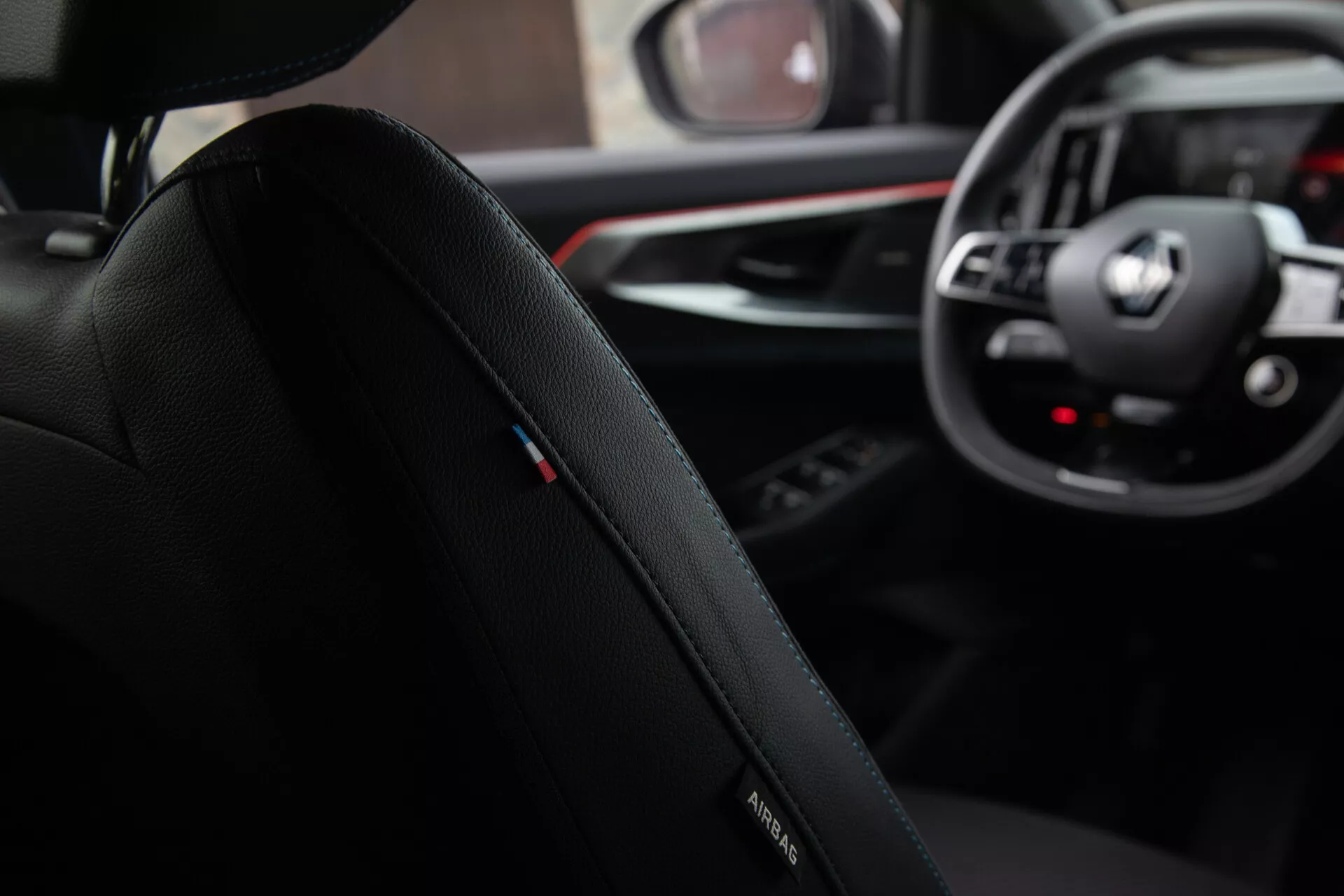 Vista interior desde la perspectiva del pasajero trasero destacando el asiento del conductor con logo de BMW, tapicería de cuero premium y costuras detalladas, enfocándose hacia el tablero con emblema de BMW en el volante, diales analógicos y pantallas digitales del sistema de infoentretenimiento, junto con un vistazo de la palanca de cambios y panel de control multimedia en un diseño de cabina sofisticado y ergonómico.