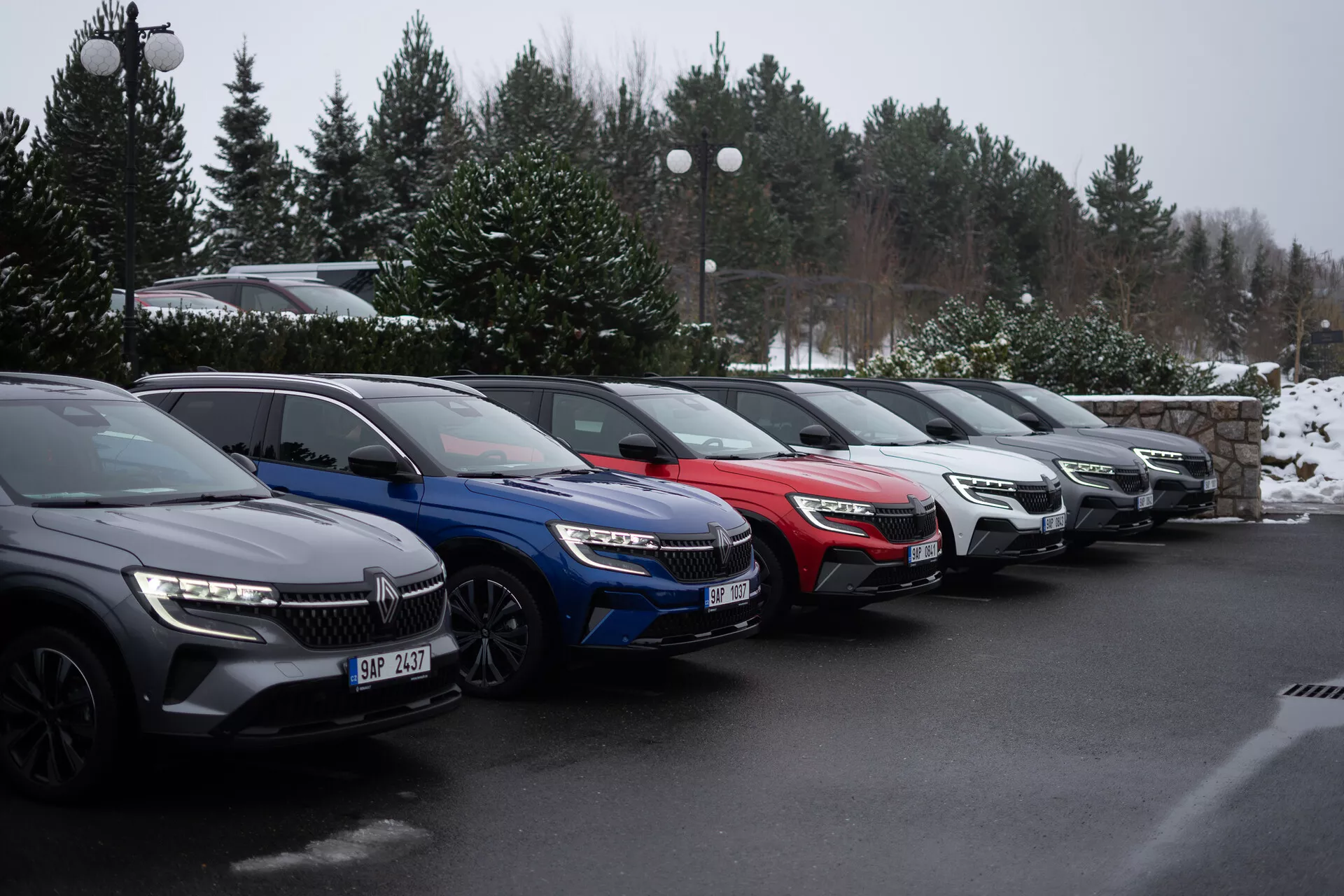 Alineación de cinco coches Renault Austral 2022 estacionados a un ángulo de 45 grados en un aparcamiento invernal, mostrando modelos en gris oscuro, azul, rojo, plateado y gris, con faros LED y rejillas frontales modernas