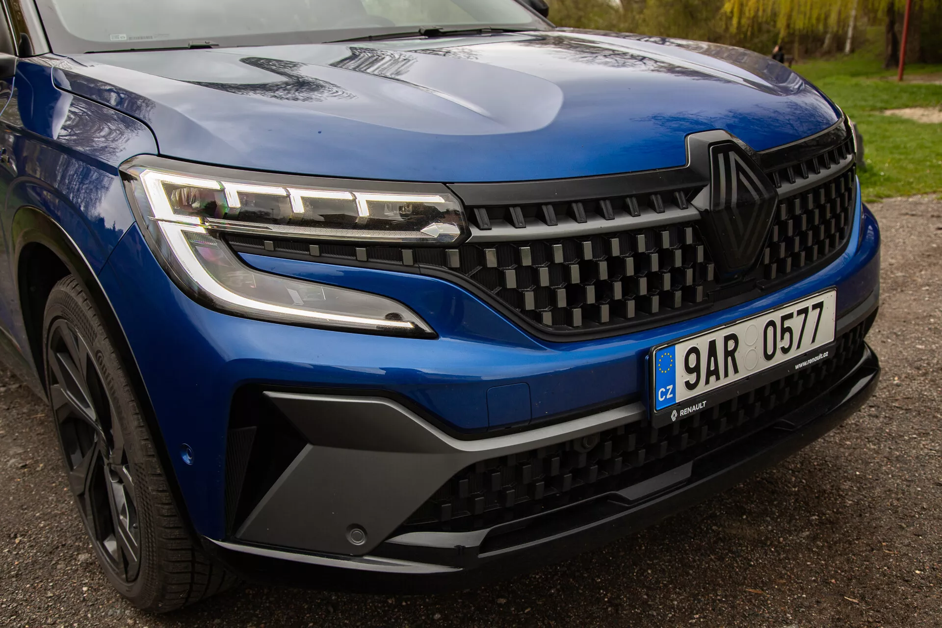Vista de primer plano del Renault Austral 2022, mostrando faros LED elegantes, un diseño de parrilla dinámico y detalles estilísticos del parachoques delantero y la rueda, enfatizando la estética y tecnología del vehículo moderno.