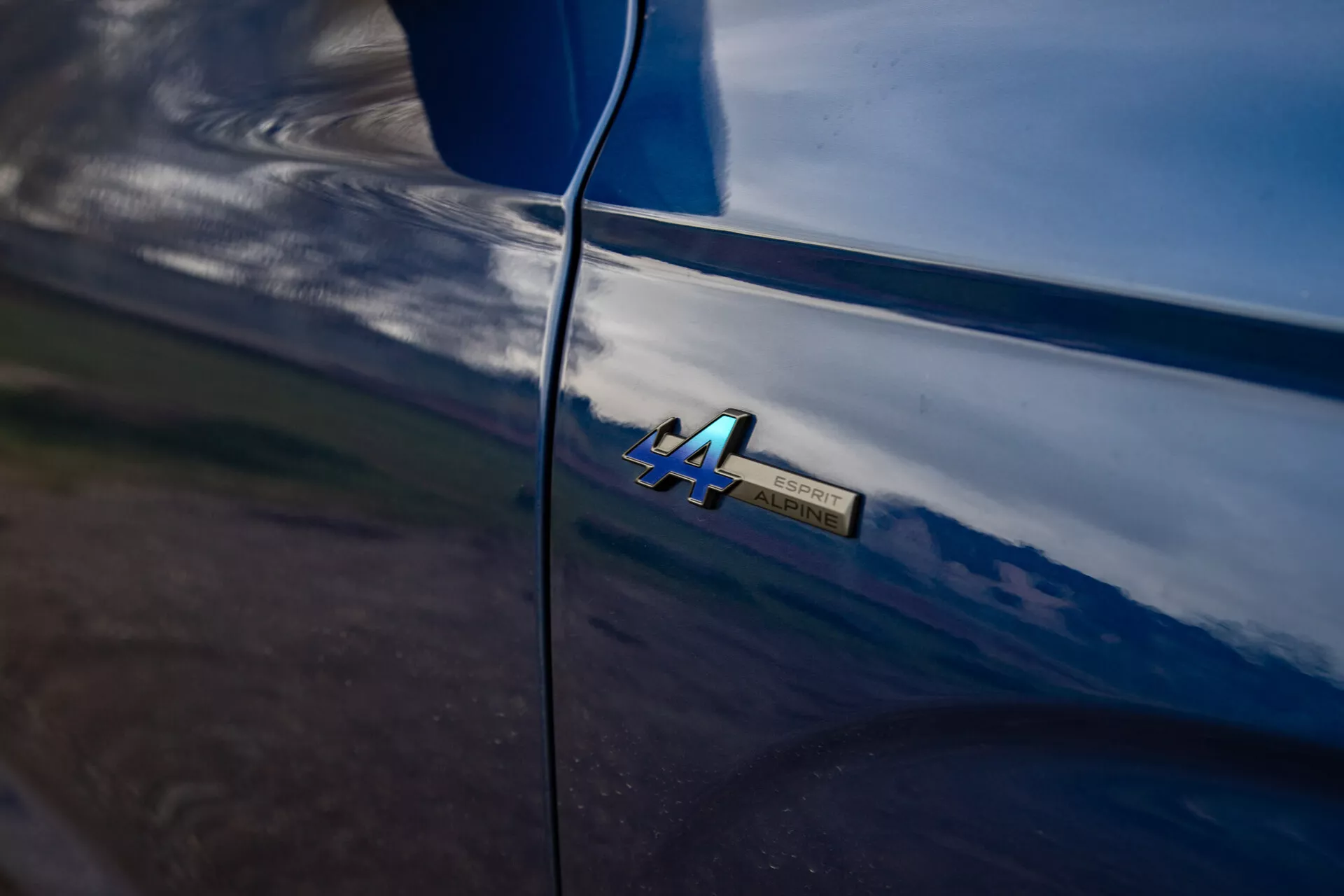 Detalle cercano de la insignia '4A' del Renault Austral 2022 en la carrocería brillante del coche con reflejos naturales y líneas suaves que sugieren un mantenimiento de alta calidad y entorno