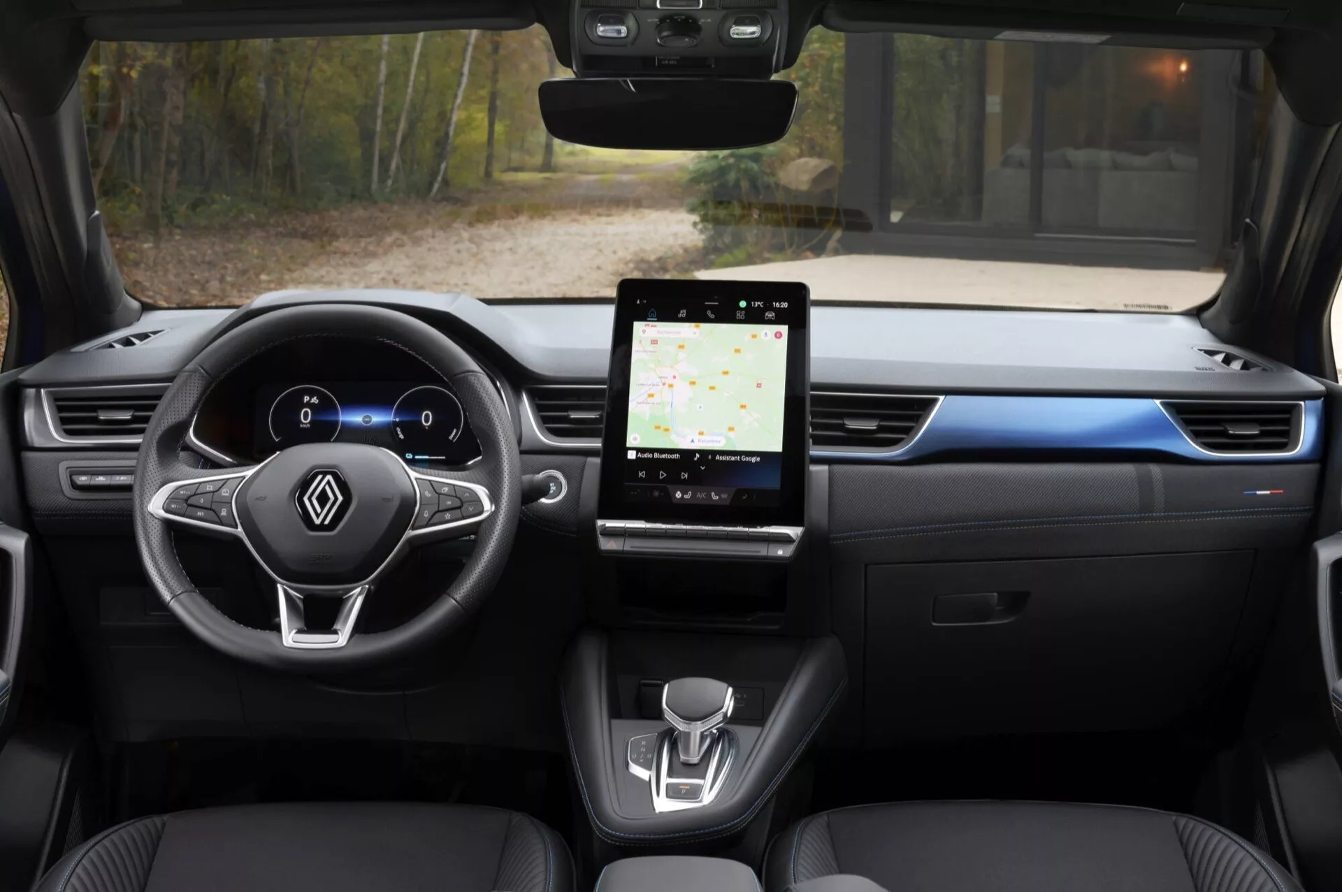 Vista interior del Renault Captur 2024 desde el asiento trasero, destacando el cuadro de instrumentos digital, volante multifunción, sistema de infoentretenimiento táctil grande y diseño minimalista de la consola central