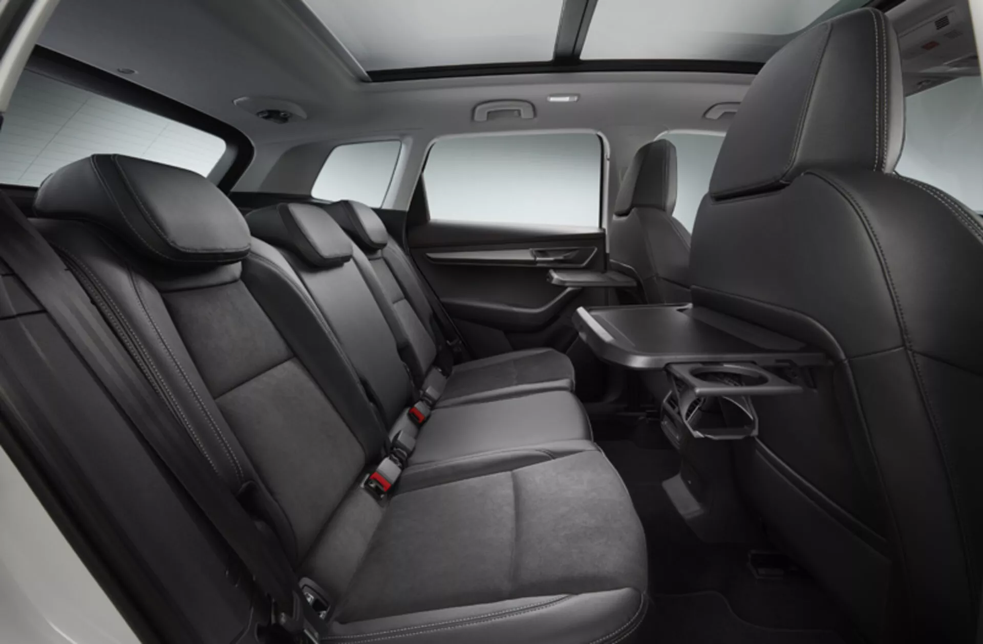 Interior del Skoda Karoq 2017 mostrando un área de asientos traseros espaciosa y cómoda con tapicería premium en dos tonos, control de clima trasero, reposabrazos abatible con portavasos y sistema de entretenimiento