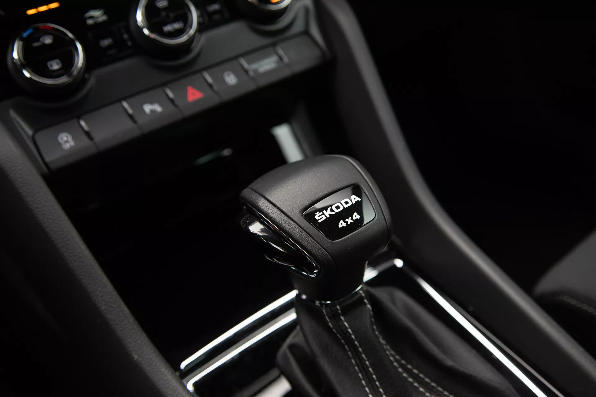 Palanca de cambios de transmisión automática de Škoda Karoq 2021 con inscripción del sistema 4x4 y logo de Škoda, rodeada de detalles interiores modernos en negro brillante y adornos metálicos.