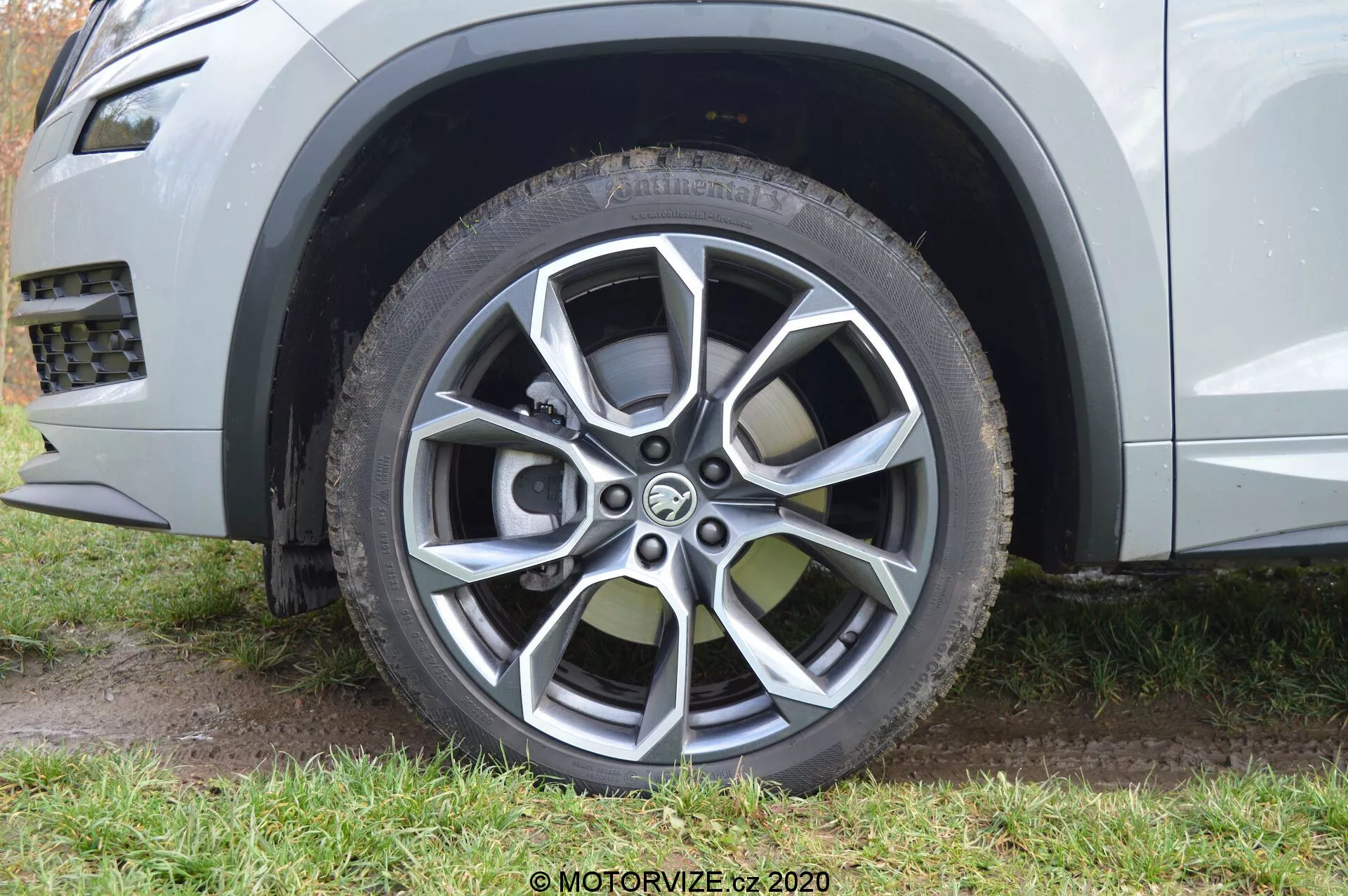 Vista de cerca del neumático delantero del lado del pasajero de un Skoda Kodiaq 2017, destacando su diseño moderno de llanta de aleación multirradio con acabados pintados y mecanizados. La llanta de aleación presenta diez radios en colores metálicos oscuro y claro, diseñado tanto para el atractivo estético como para la protección contra los bordillos. La imagen también resalta la llanta de todo terreno o todo clima con su dibujo visible y diseño de protector de llanta, y muestra parcialmente el color metálico plateado o gris claro de la carrocería junto con un elemento de recorte plástico alrededor del arco de la rueda, aludiendo a la estética robusta y capaz fuera de carretera del SUV.
