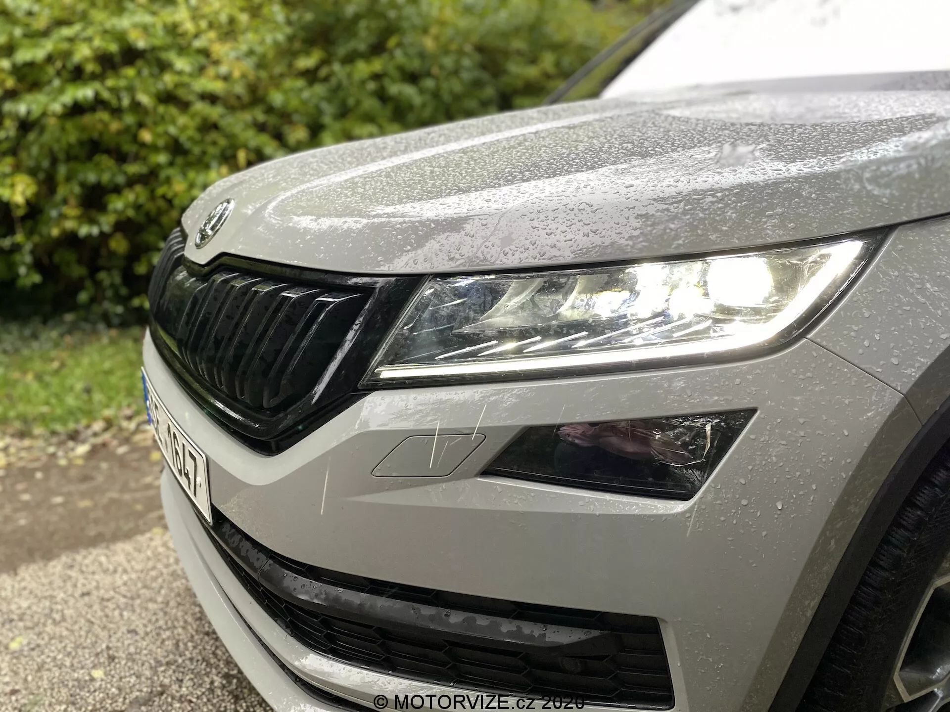 Vista en primer plano del cuarto delantero izquierdo de un Škoda Kodiaq 2017, mostrando el faro izquierdo con diseño moderno de LED, parte del capó con gotas de lluvia y la distintiva parrilla de Škoda con elementos horizontales.
