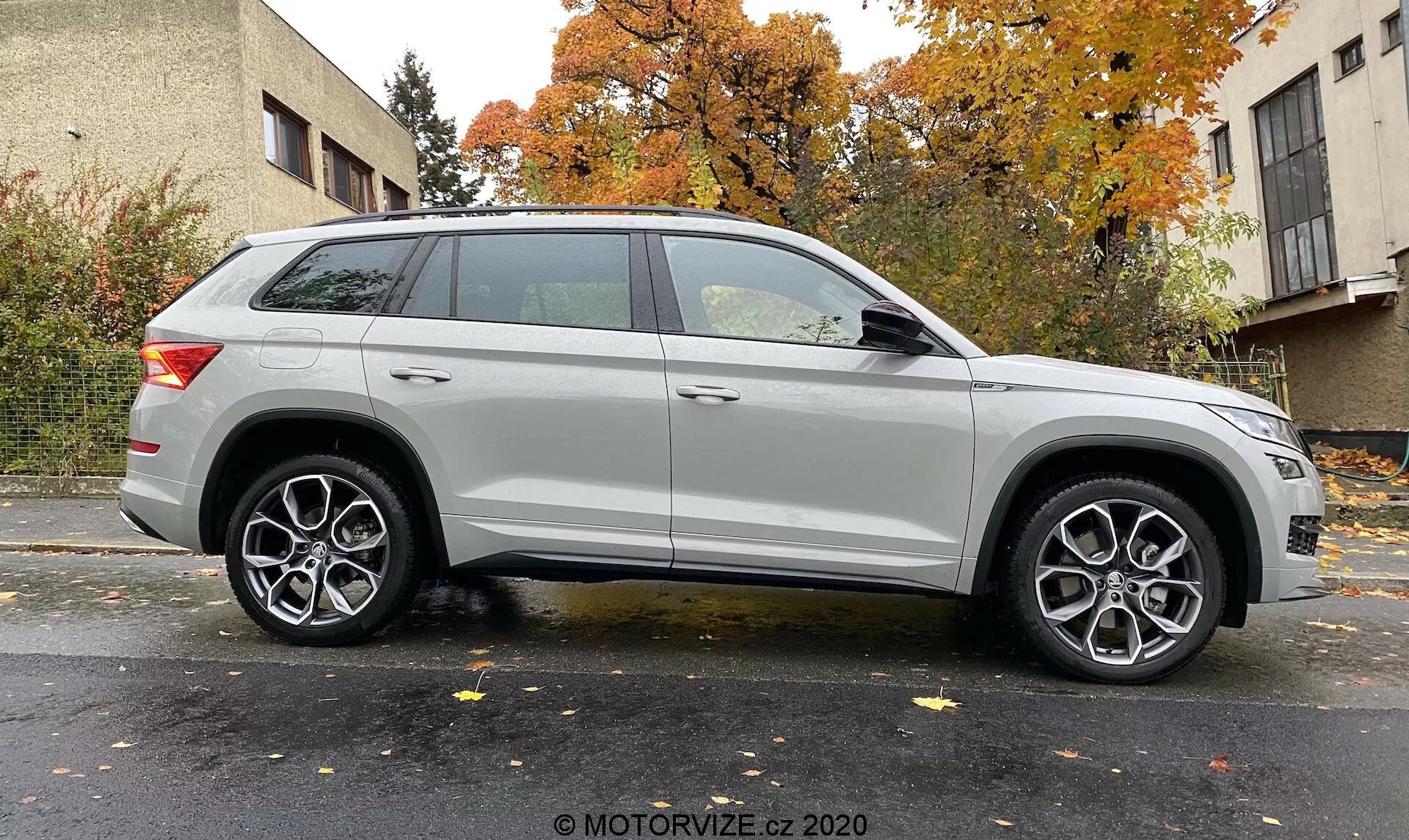 Perfil lateral de un SUV Skoda Kodiaq 2017 plateado capturado desde un ángulo ligeramente inclinado, destacando la rueda delantera y el guardabarros. Muestra la longitud del vehículo y elementos de diseño como faros modernos, llantas de aleación multirradio, línea de carácter prominente, rieles de techo y luces traseras elegantes. Fondo neutro con iluminación uniforme. Crédito de la foto: MOTORVIZE.cz 2020.
