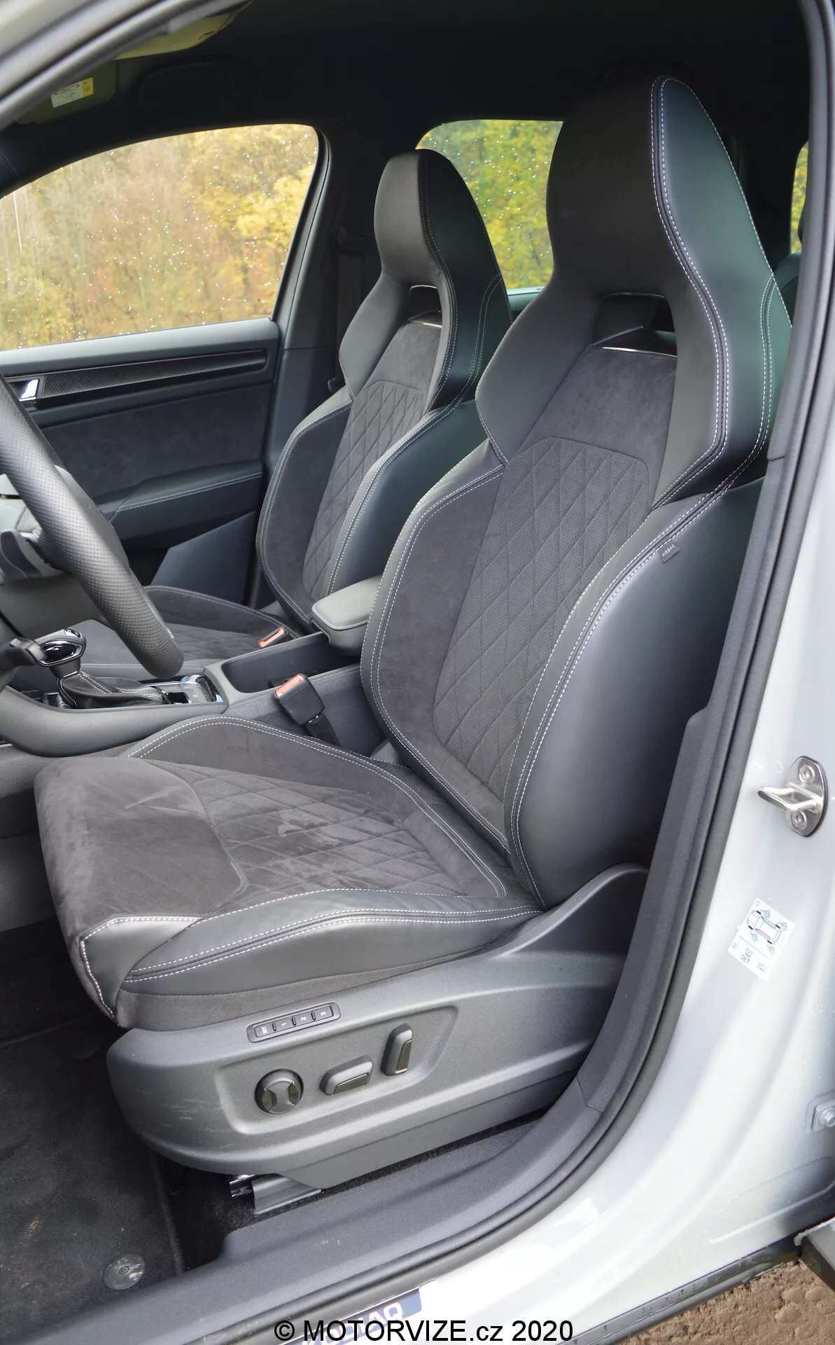 Vista interior de un Skoda Kodiaq 2017 centrada en el asiento del conductor y su entorno, con tapicería de cuero negro con costuras de diamante, reposacabezas integrado, soporte lateral para conducción dinámica y ajustes electrónicos del asiento con botones de control. Los elementos visibles incluyen el marco inferior de la puerta con placa de umbral y una unidad de altavoz, indicativos de un interior lujoso y deportivo con tecnología avanzada de asientos.