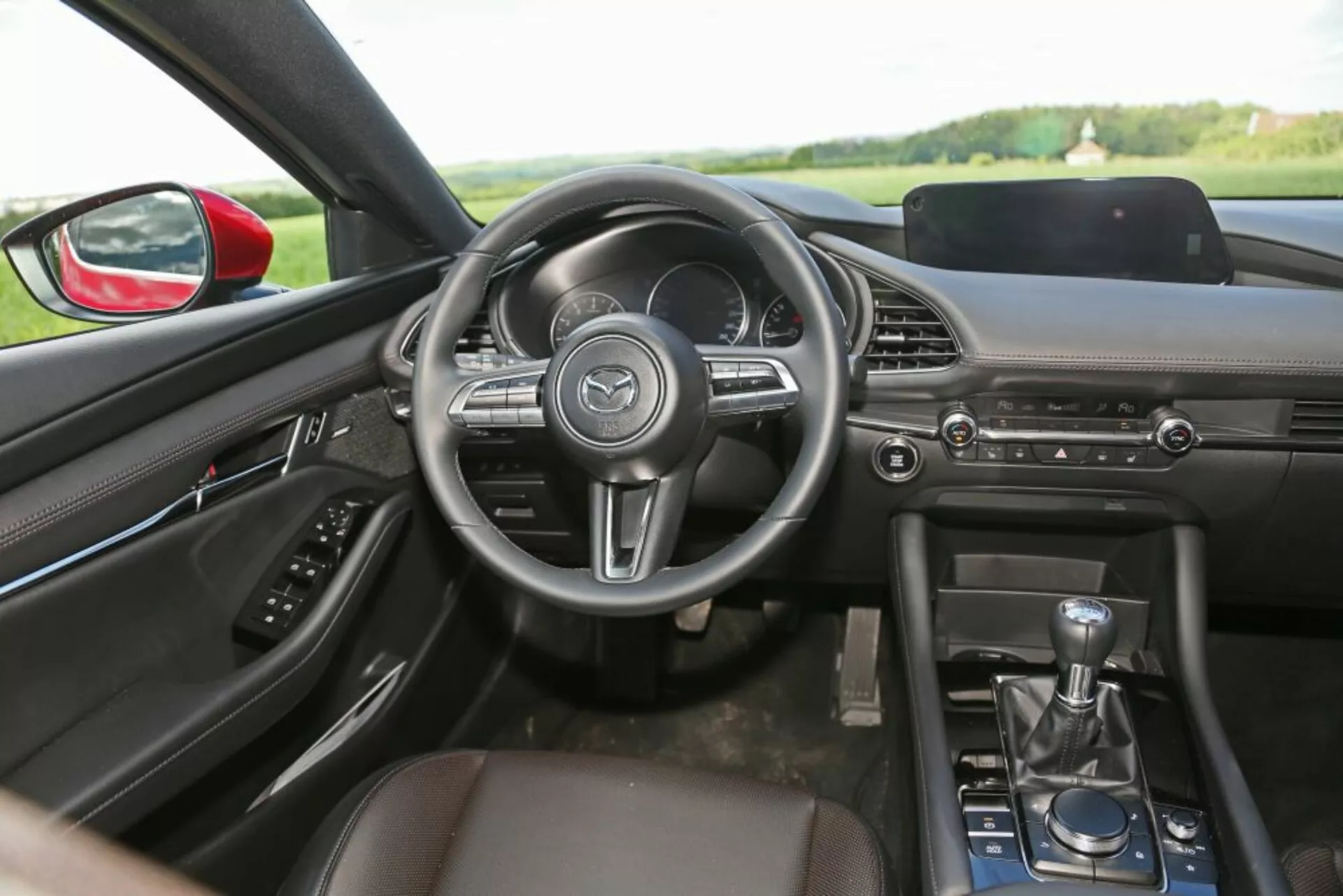 Vista interior de un Skoda Scala 2019 desde el asiento trasero destacando el tablero, volante, consola central, palanca de cambios manual y diseño de la cabina delantera con características de tecnología y comodidad.