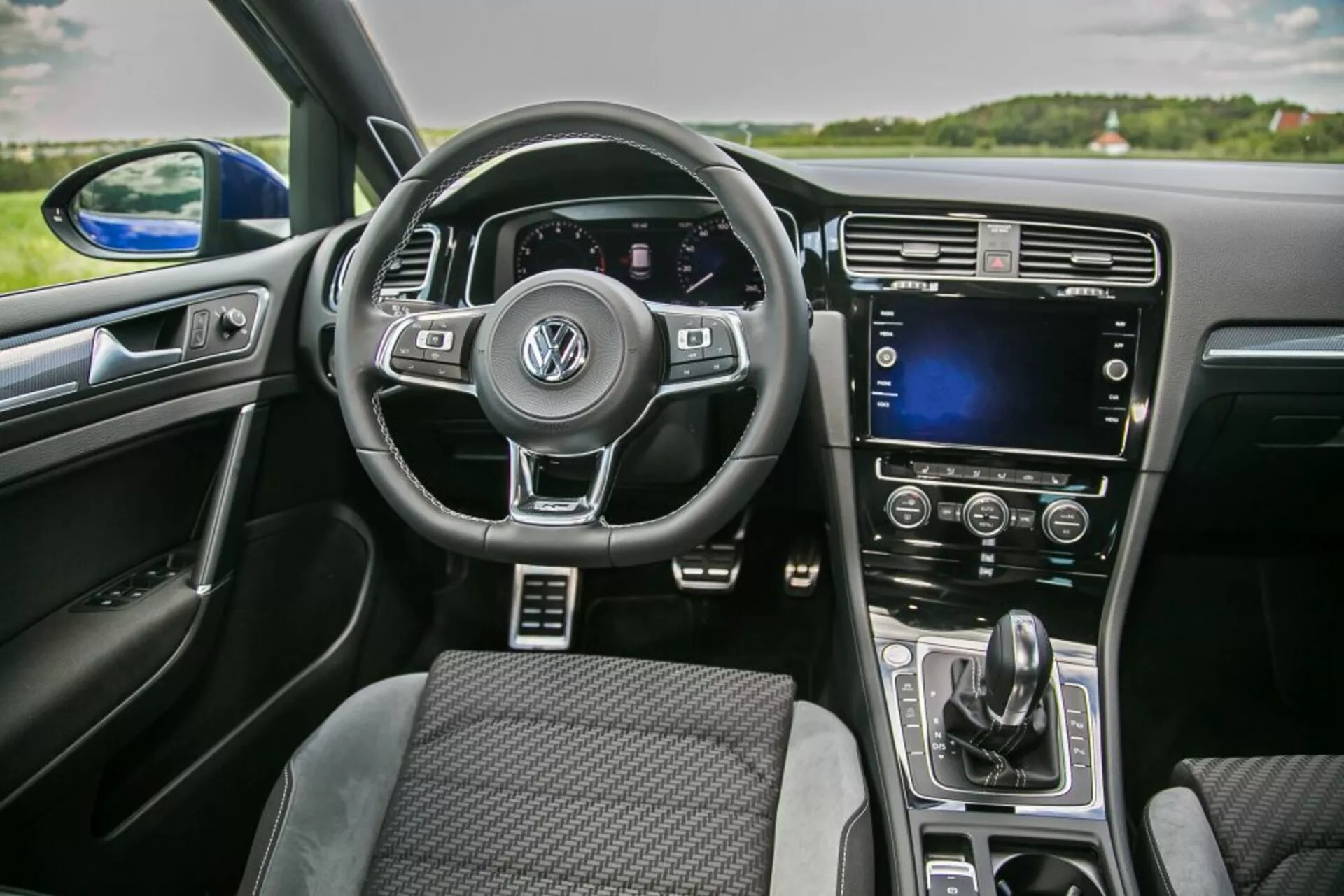 Vista interior de un Skoda Scala 2019 desde la perspectiva del pasajero delantero con volante multifunción con logo de Volkswagen, cuadro de instrumentos digital, pantalla táctil en la consola central y control automático del clima
