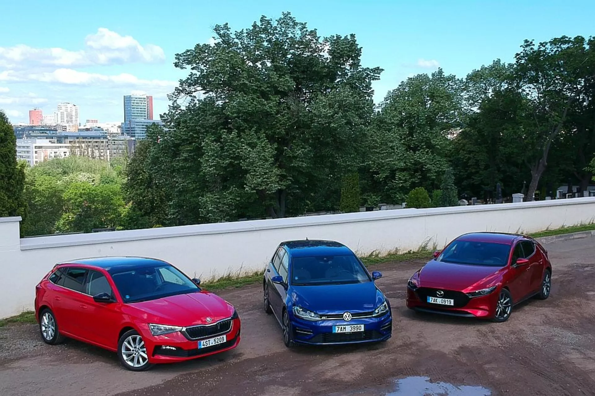 Hatchbacks Skoda Scala de 2019 aparcados lado a lado en un entorno urbano, mostrando colores rojo, azul y burdeos con una toma en ángulo alto desde una posición elevada, destacando sus ruedas de aleación, faros halógenos y diseños aerodinámicos