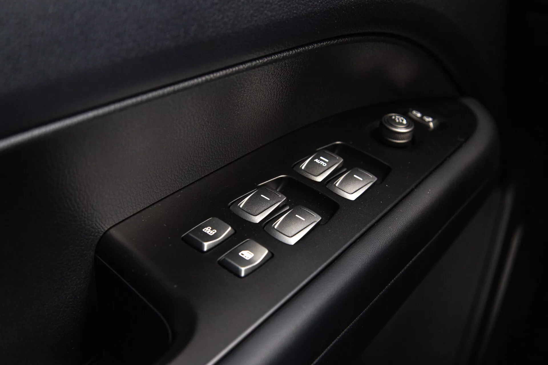 Vista detallada de los controles de la puerta interior del SsangYong Musso 2022 mostrando ajustes de ventana y espejo eléctricos, botones iluminados para facilidad de uso, en un diseño ergonómico de alta calidad