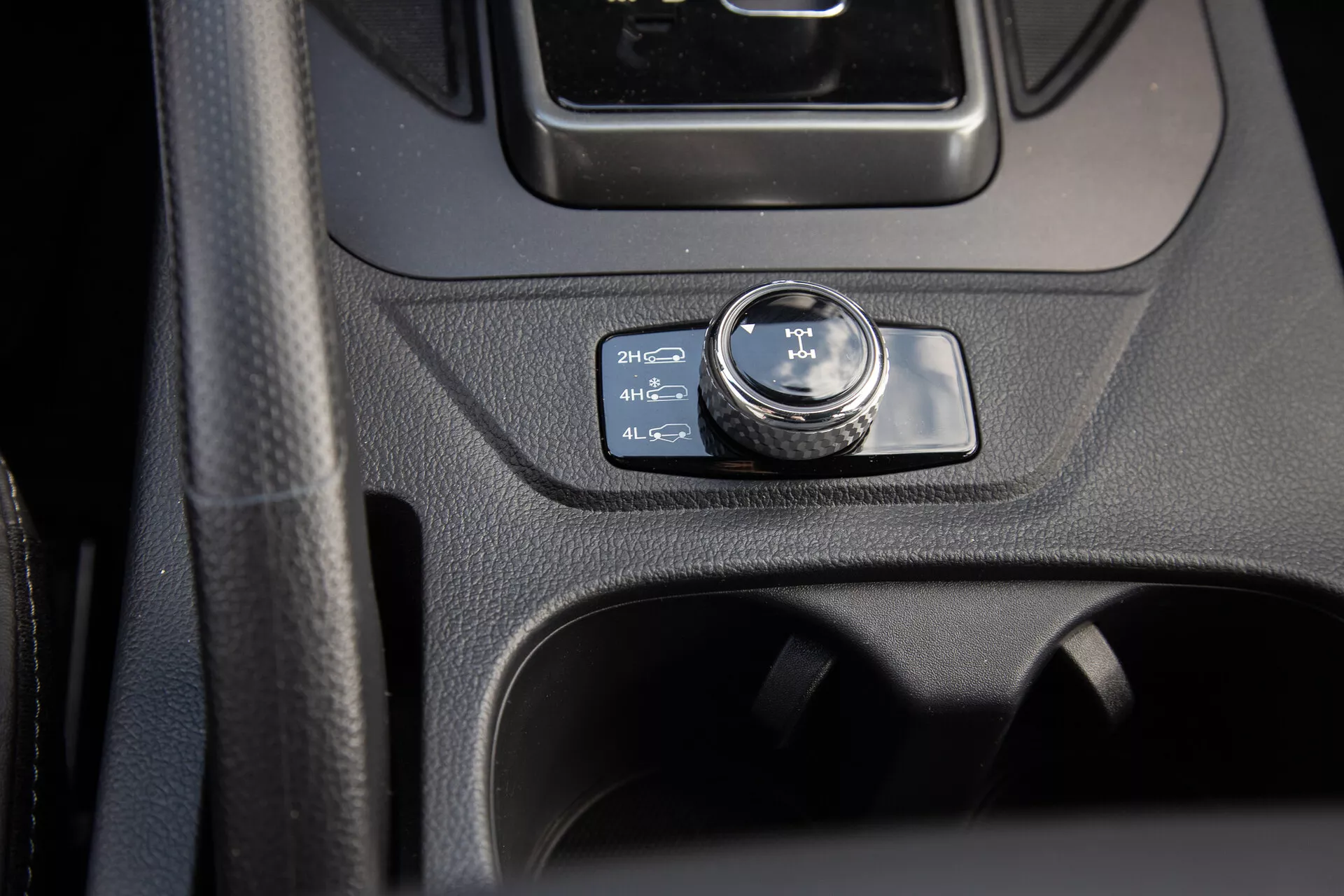 Vista detallada de la consola central de SsangYong Musso 2022 con enfoque en el dial de control de 4WD en posición 2H, abarcando diseño interior moderno y características de utilidad